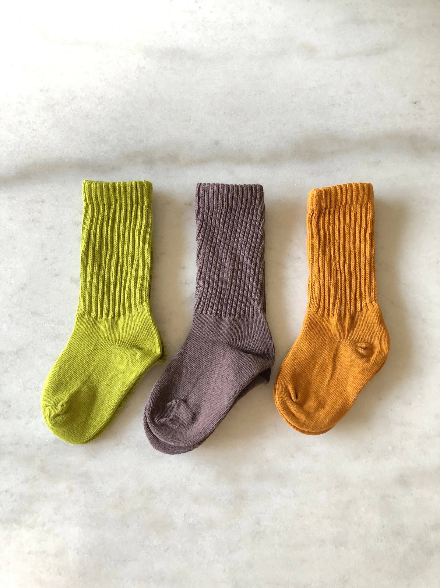 Three pairs of socks in green, taupe, and orange on a white background