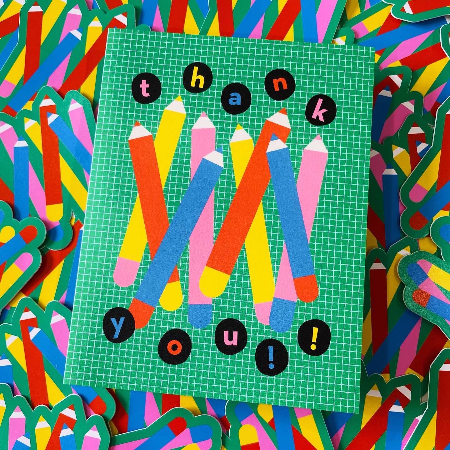 Colorful card with pencils and 'thank you!' text on a grid background, surrounded by more colorful pencils.