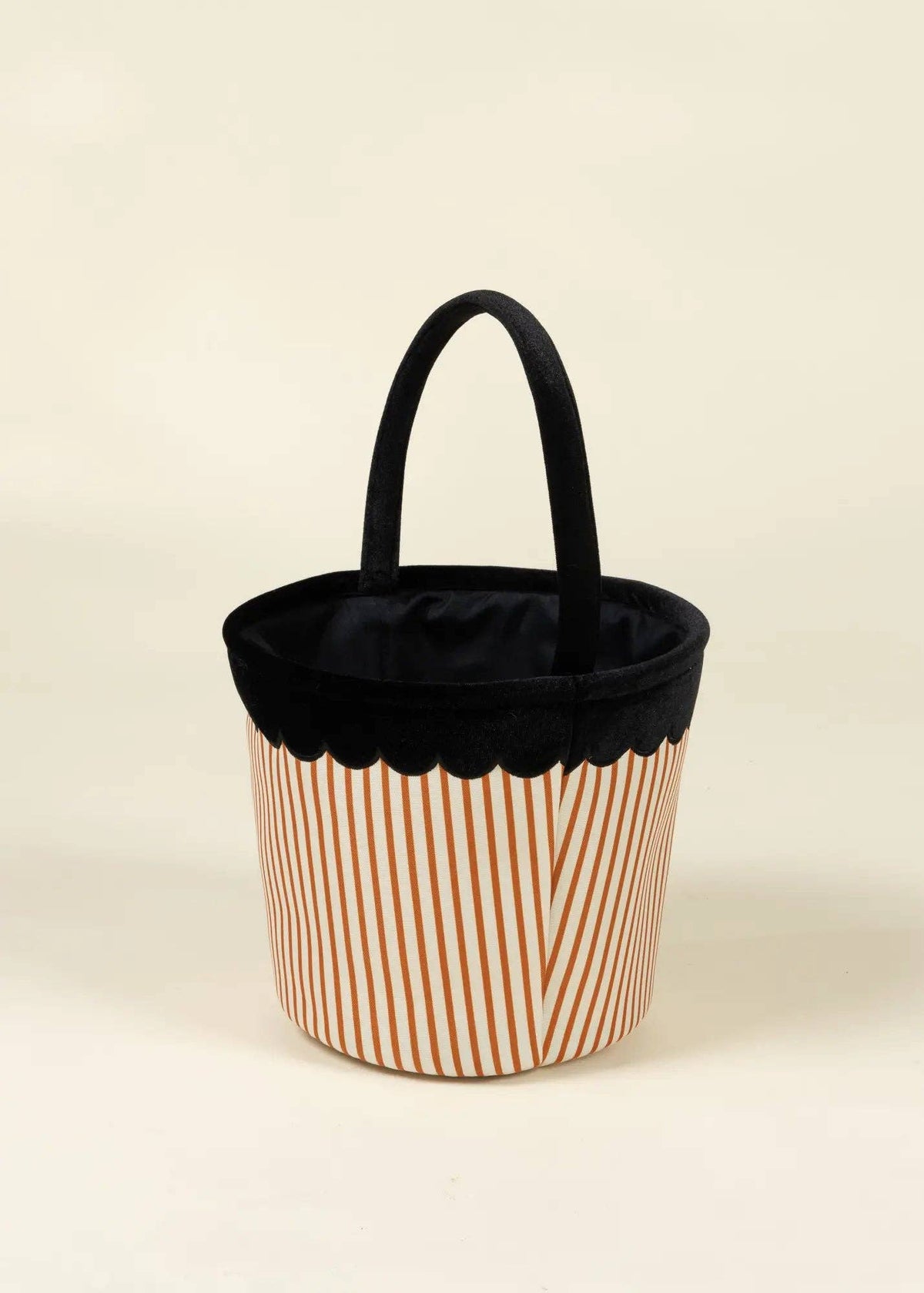 A cylindrical fabric tote bag with a black top handle, a black scalloped inner rim, and a body featuring thin vertical orange stripes on a white background.