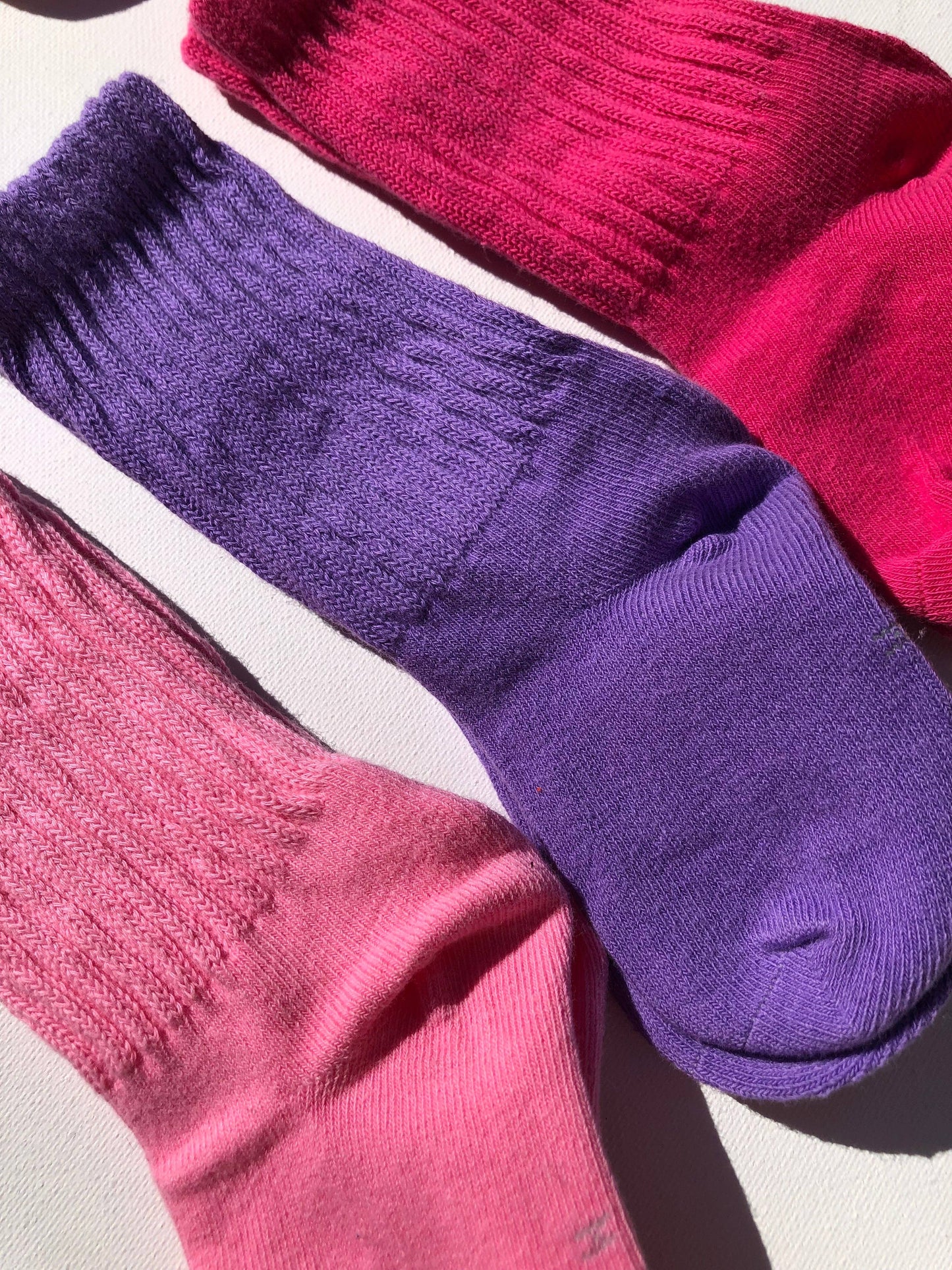 Two pairs of socks, one purple and one pink, on a light gray background.