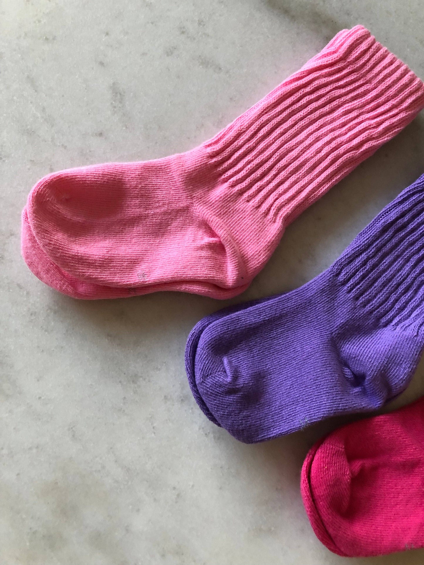 Two pairs of colorful socks on a light gray surface