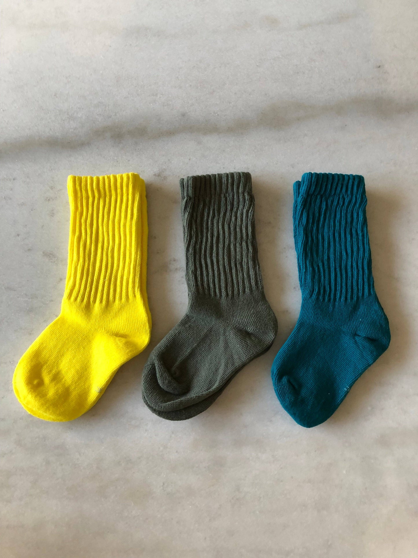 Three socks in yellow, gray, and blue on a light gray background