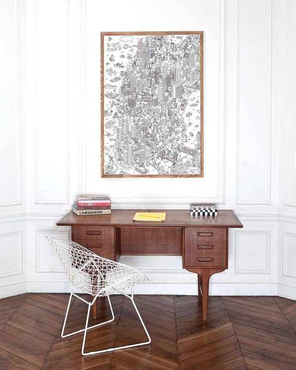Wooden desk with a chair in a room with a large framed map on the wall.