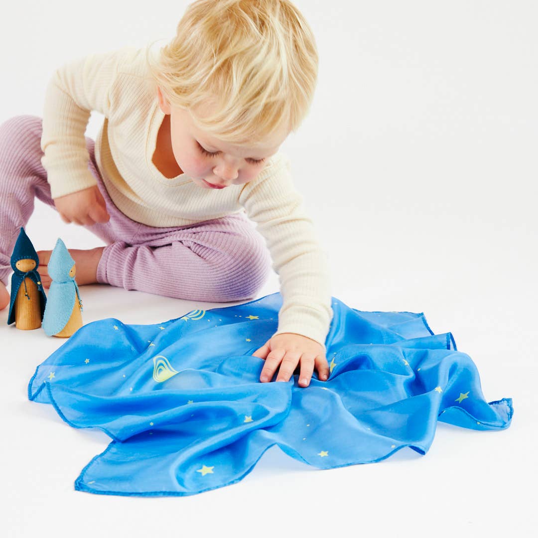 Child playing with a blue fabric on a white surface