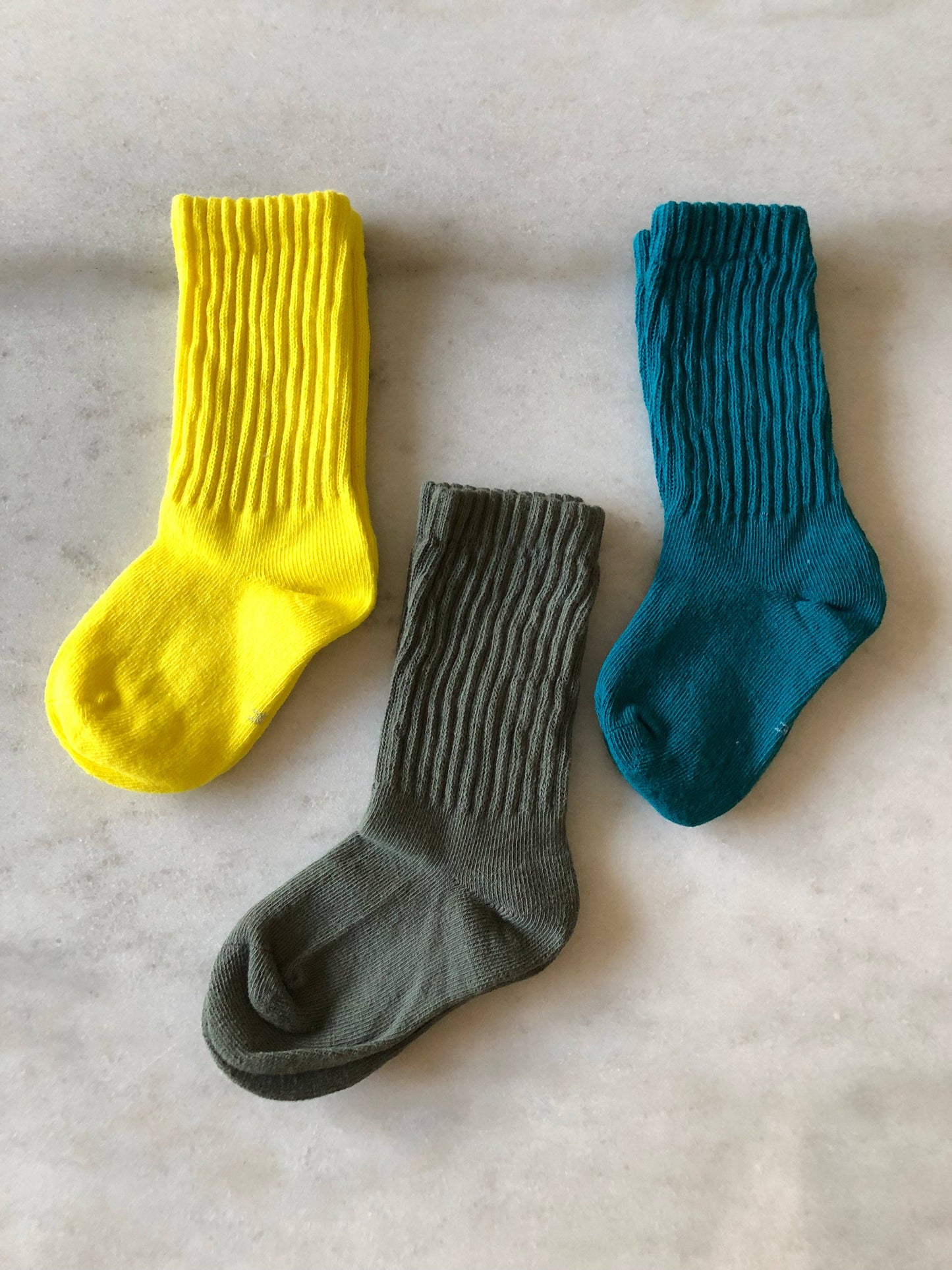 Three socks in yellow, gray, and teal on a light gray background