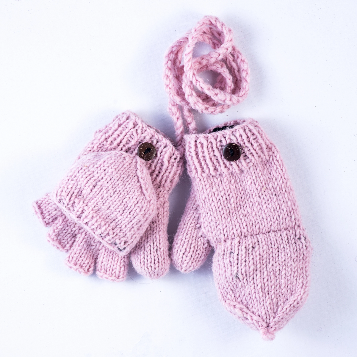 A pair of light pink hand-knit baby mittens with a matching knit wrist warmer loop, featuring small dark buttons on the back of each mitten, shown on a plain white background.