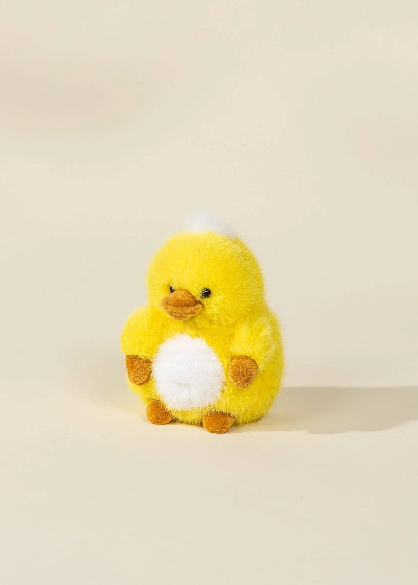 Yellow plush duck toy on a beige background