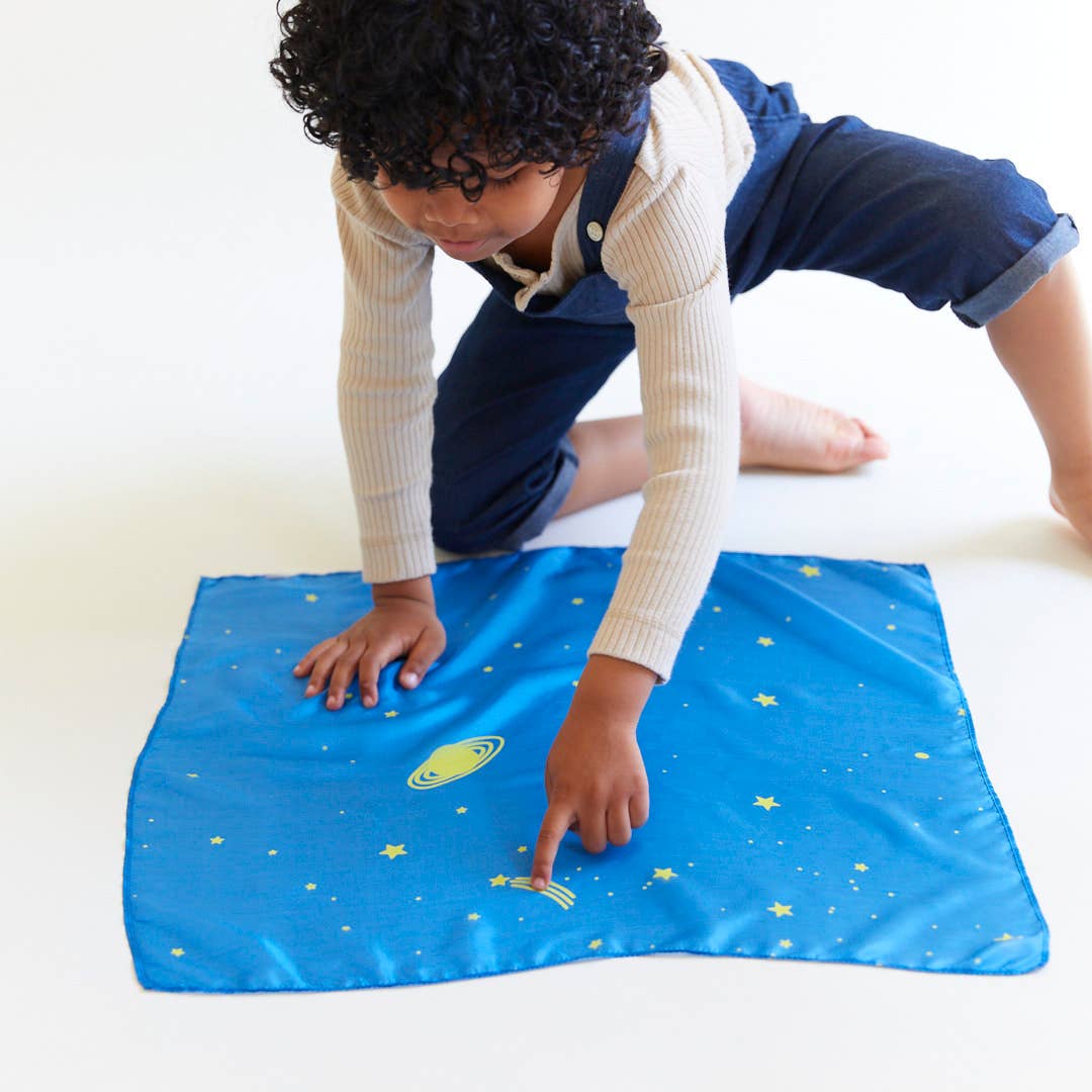 Child playing with a blue mat featuring space-themed designs on a white background