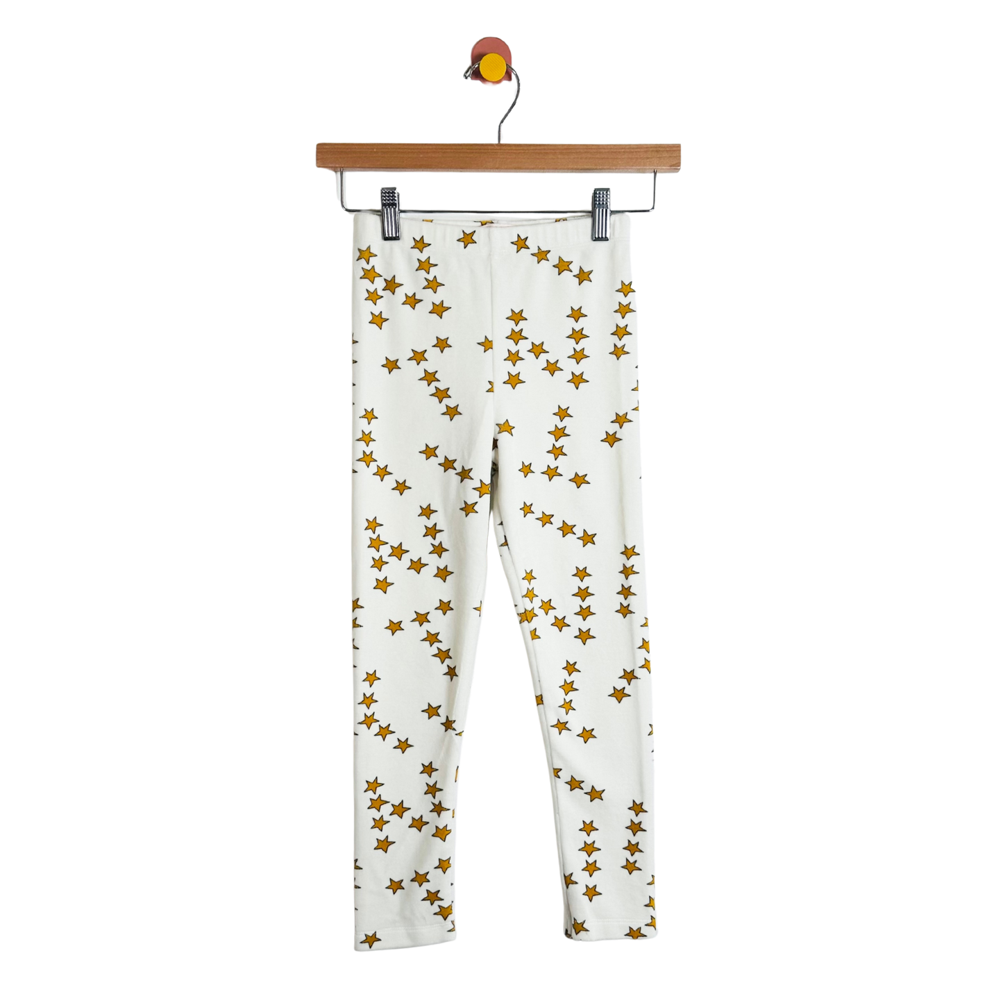 White pants with gold star pattern on a hanger against a white background