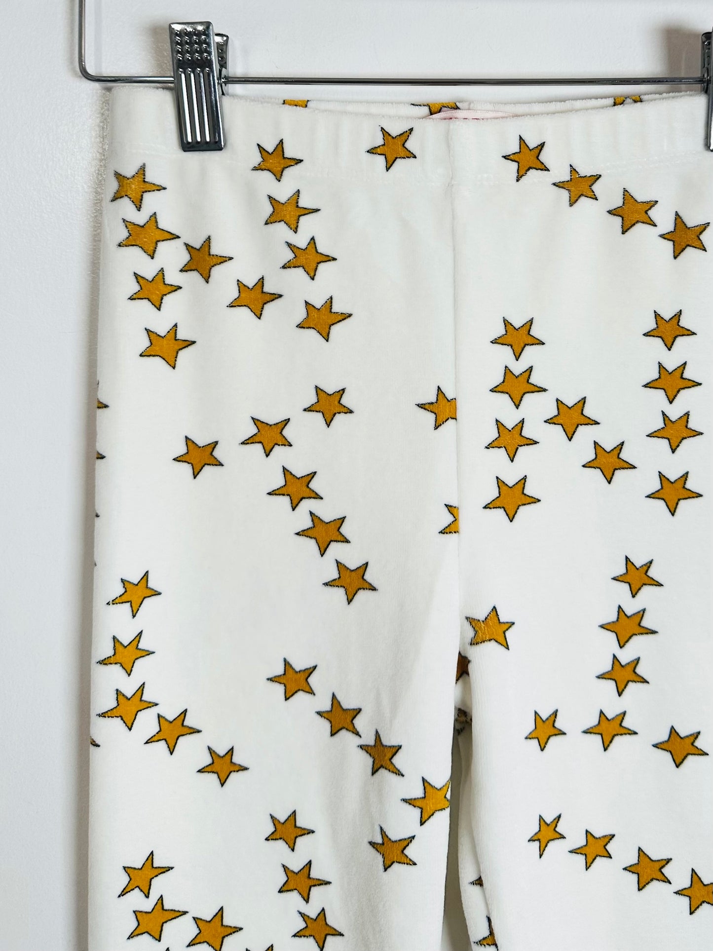 White fabric with gold star pattern hanging on a rack.
