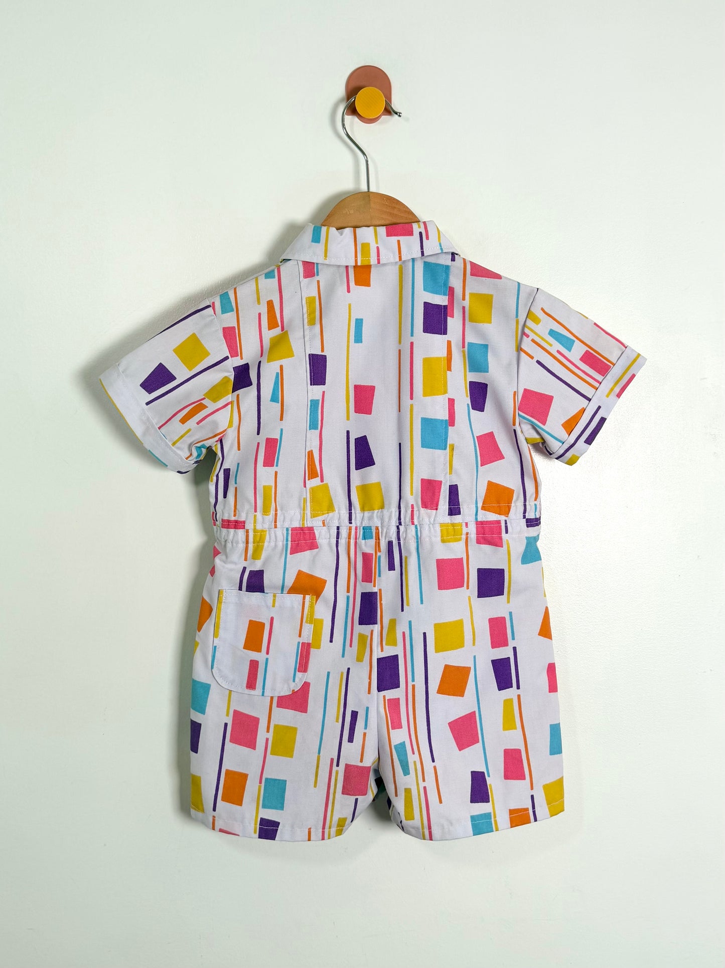Colorful baby romper with geometric pattern on a white background