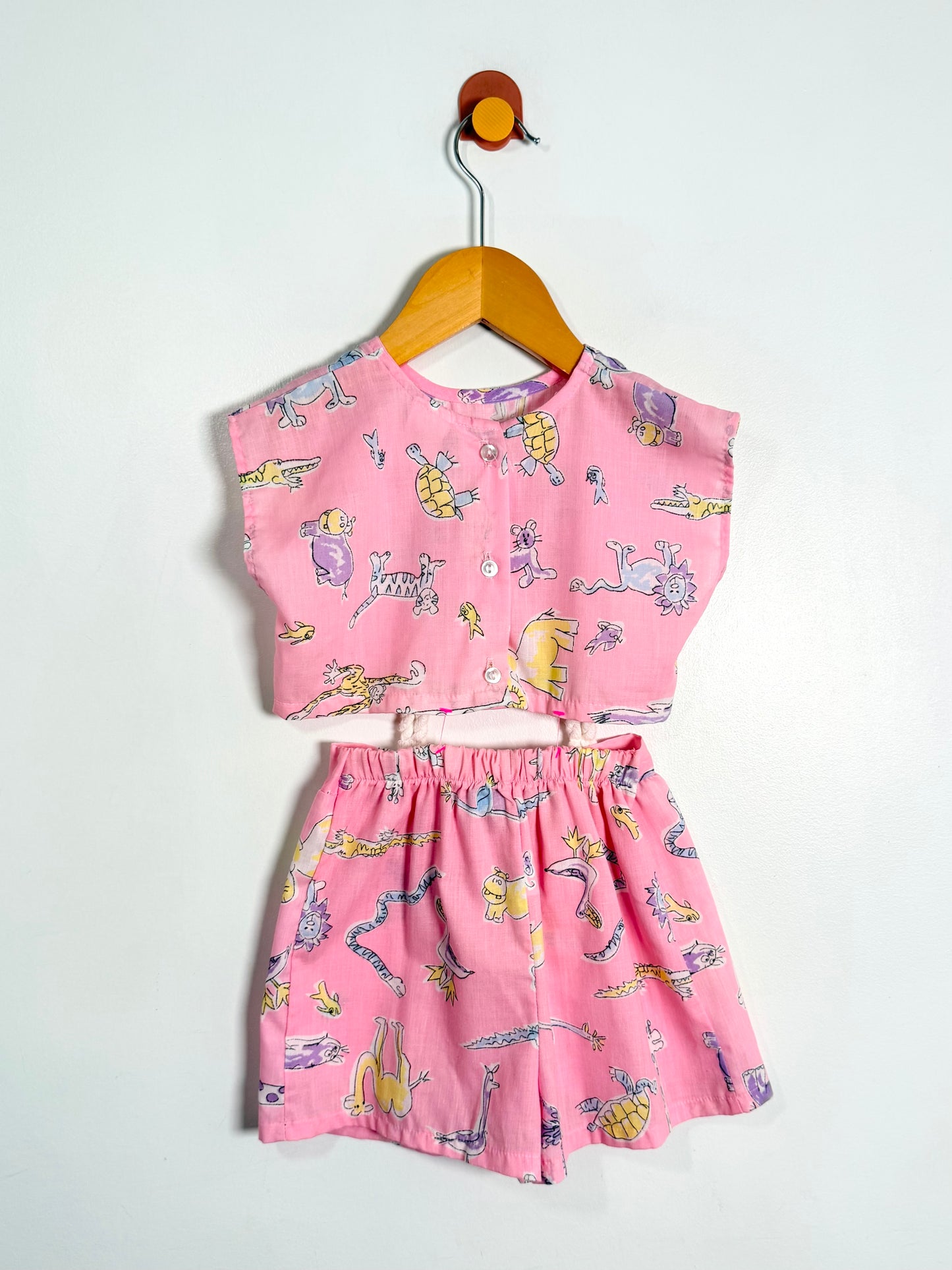 Pink children's outfit with cartoon print on a white background
