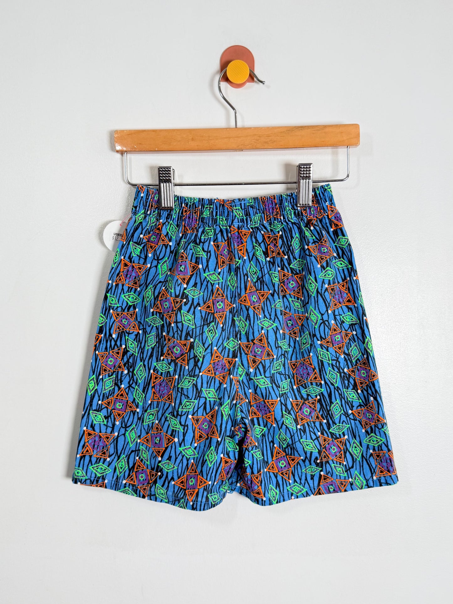 Blue patterned shorts on a hanger against a white background