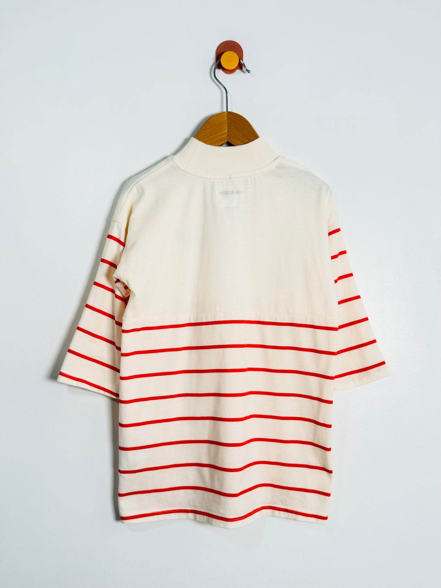White dress with red stripes on a hanger against a light gray background
