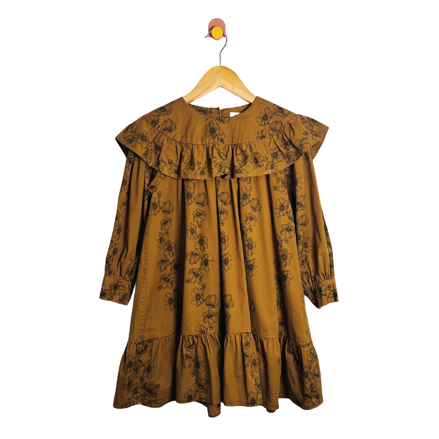 Mustard yellow dress with floral pattern on a hanger against a white background