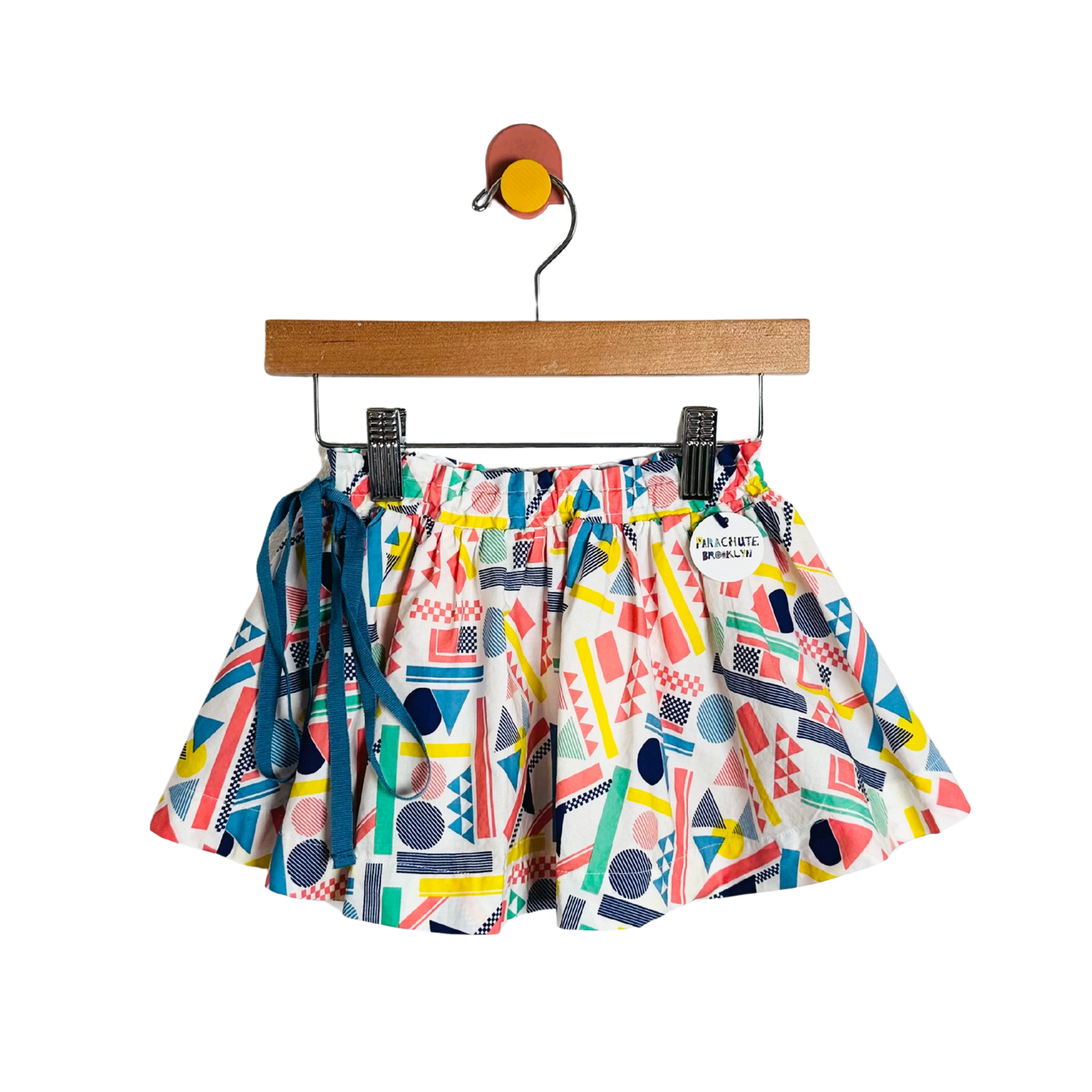 Colorful geometric-patterned shorts on a hanger against a white background