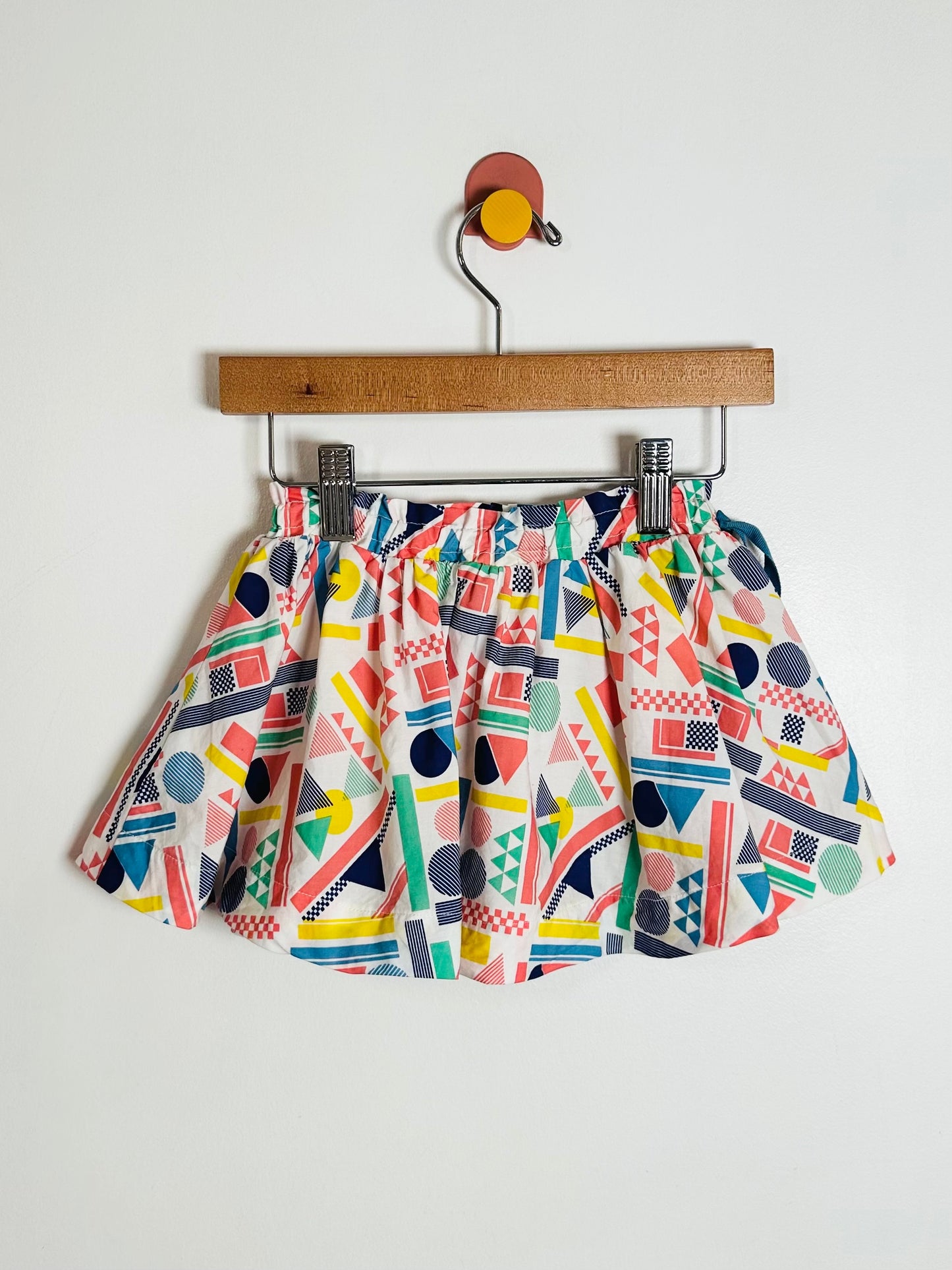 Colorful geometric-patterned skirt on a hanger against a white background