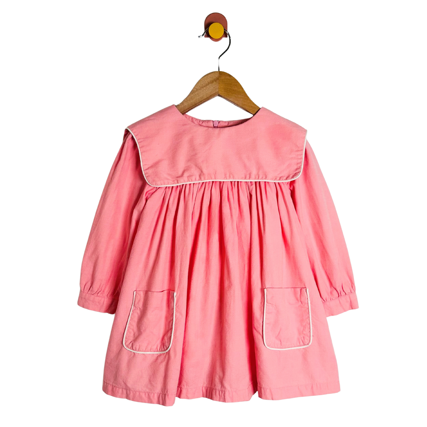 Pink dress on a hanger against a white background