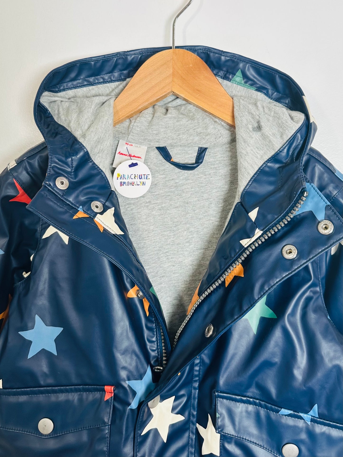 Children's blue raincoat with star patterns on a hanger against a white background