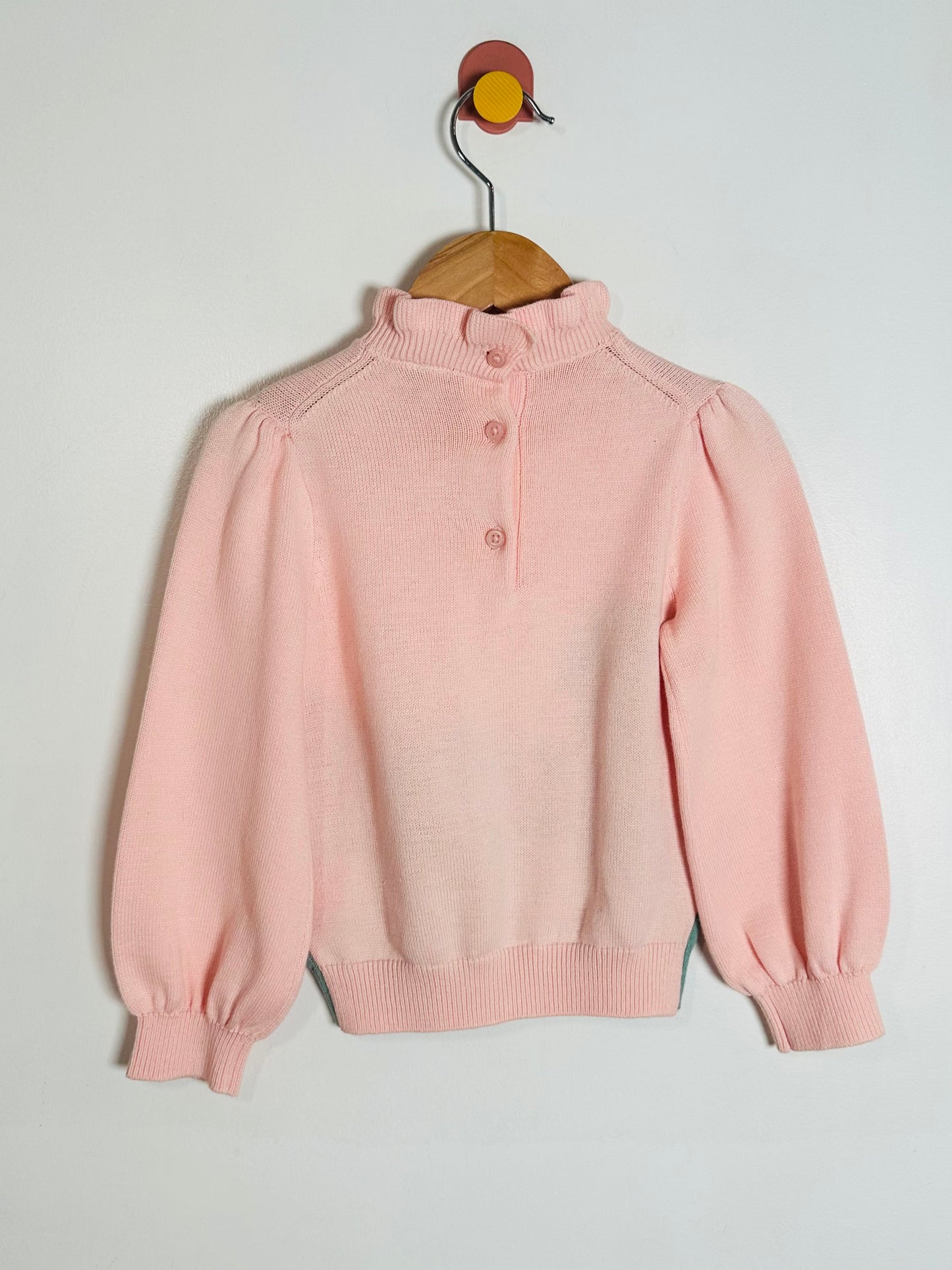 Pink sweater on a hanger against a light gray background