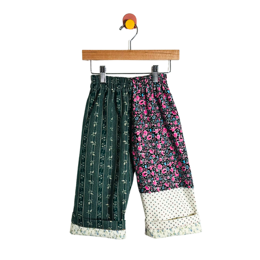 Colorful patchwork pants on a hanger against a white background