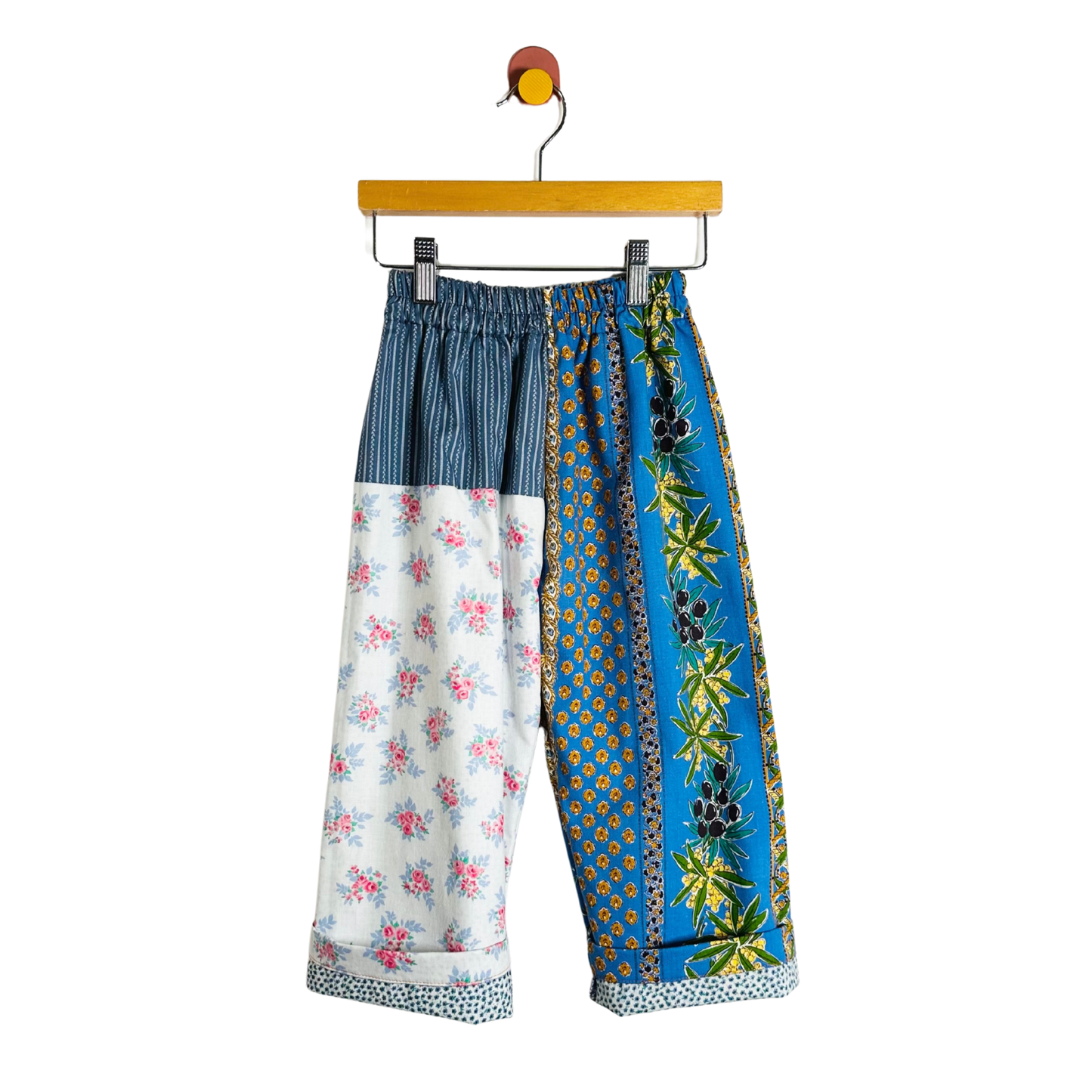 Colorful patchwork pants on a hanger against a white background