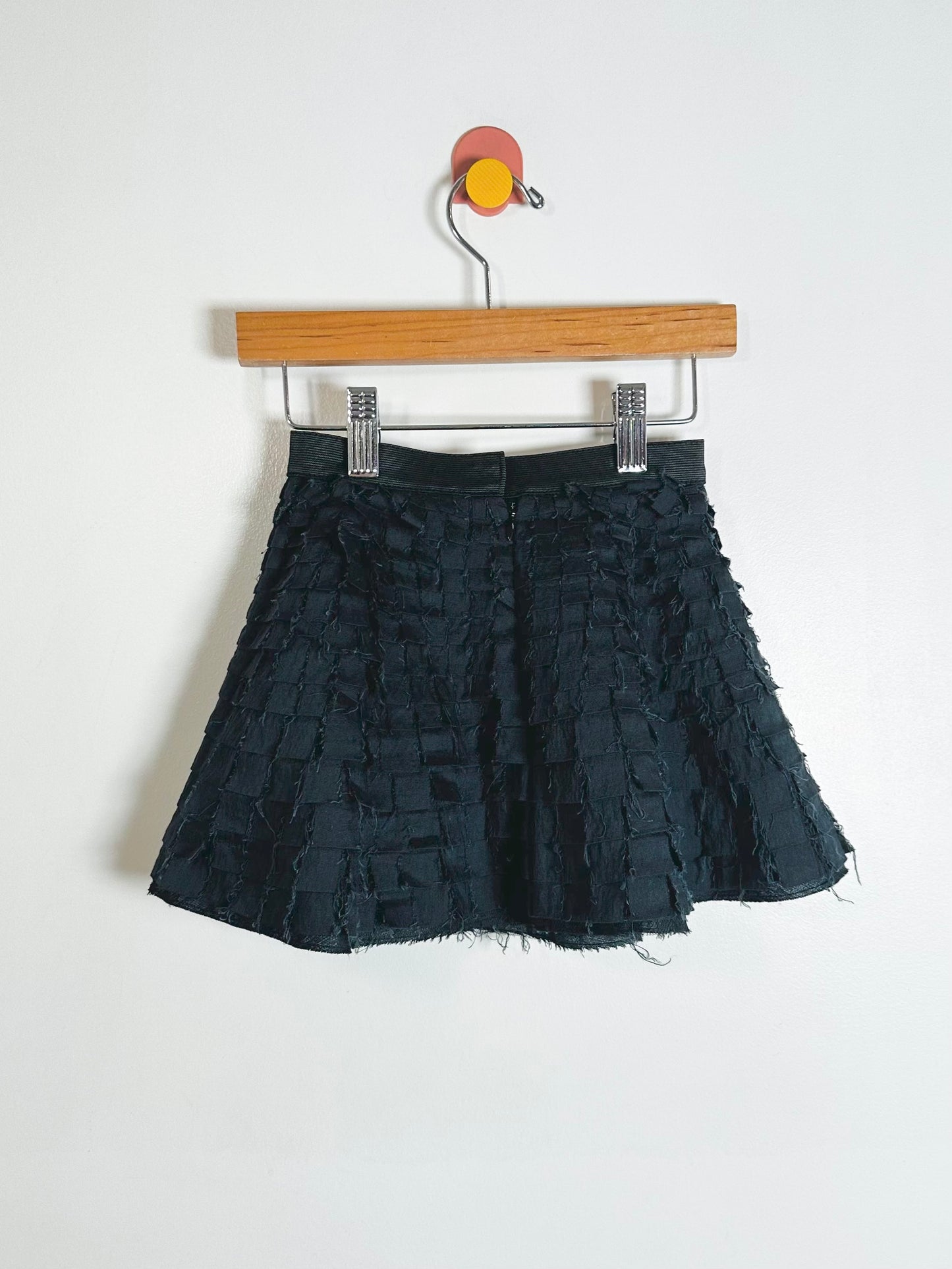 Black textured skirt on a wooden hanger against a white background