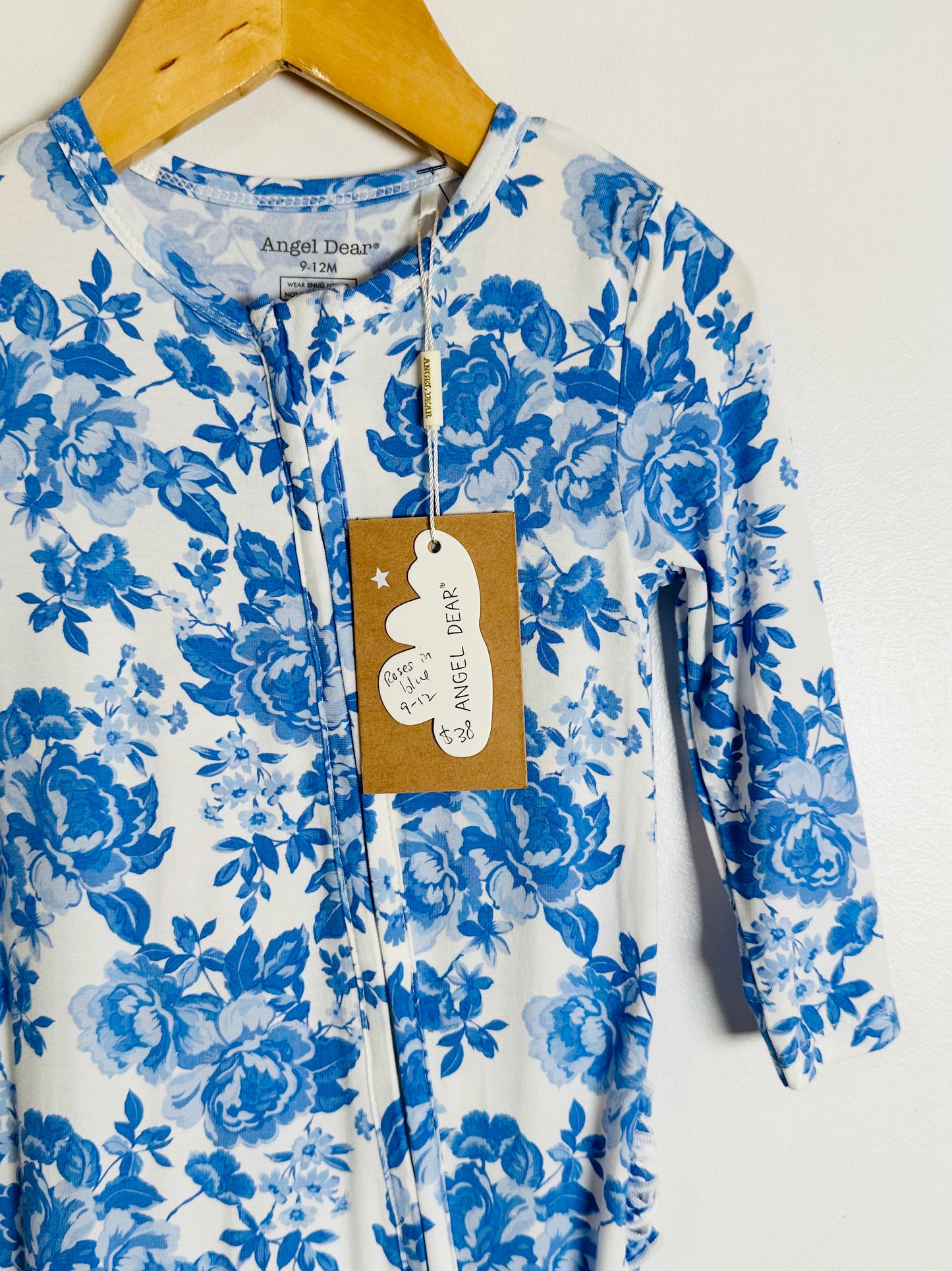 Blue floral onesie on a hanger with a visible brand tag.