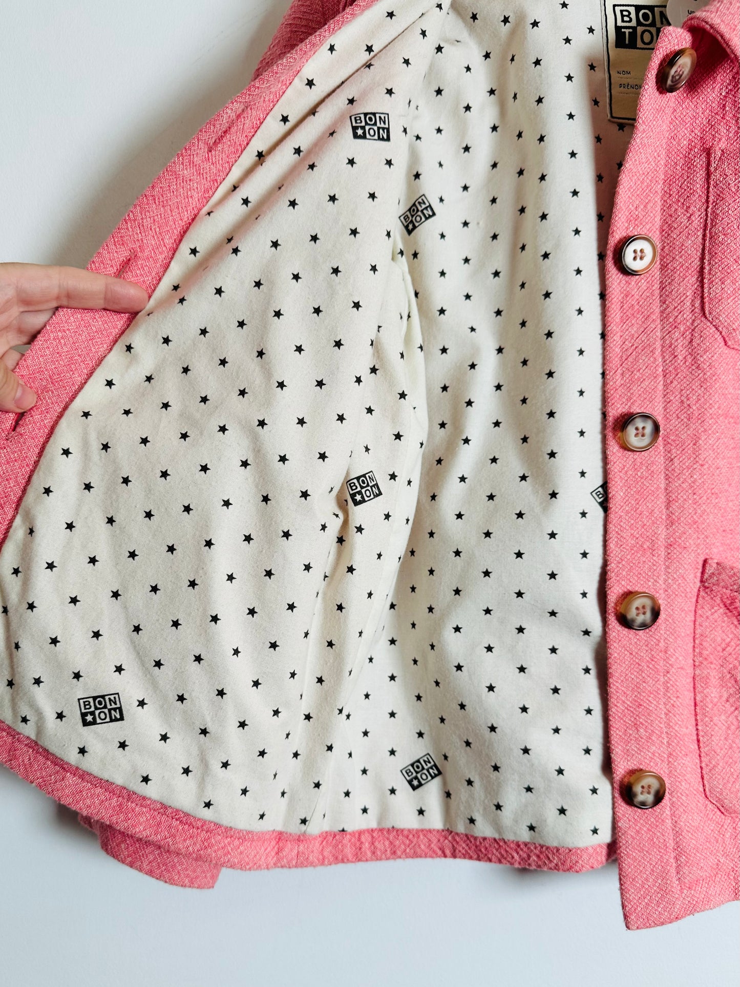 Pink jacket with star patterned lining on a light gray background