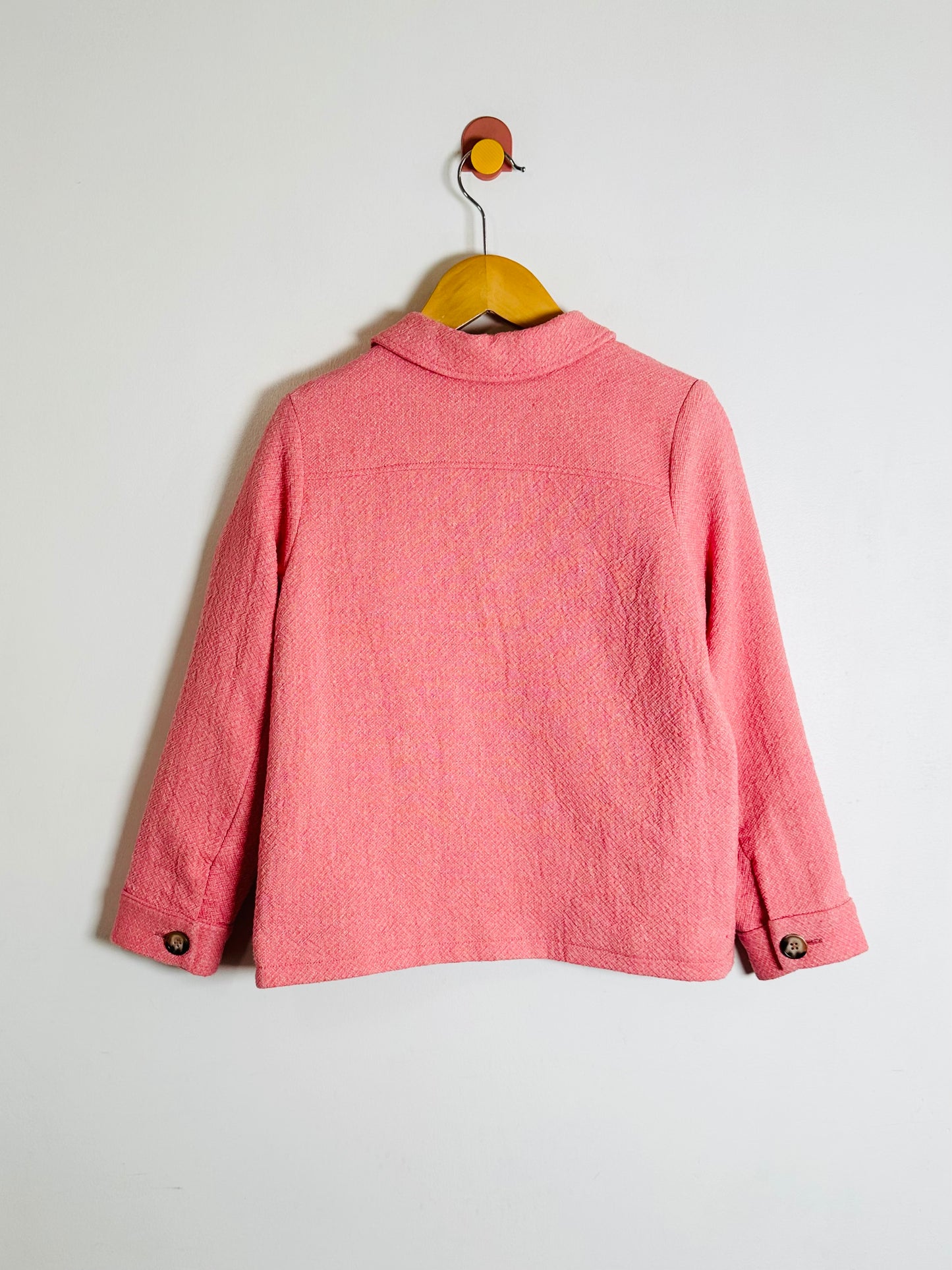 Pink jacket on a hanger against a white background