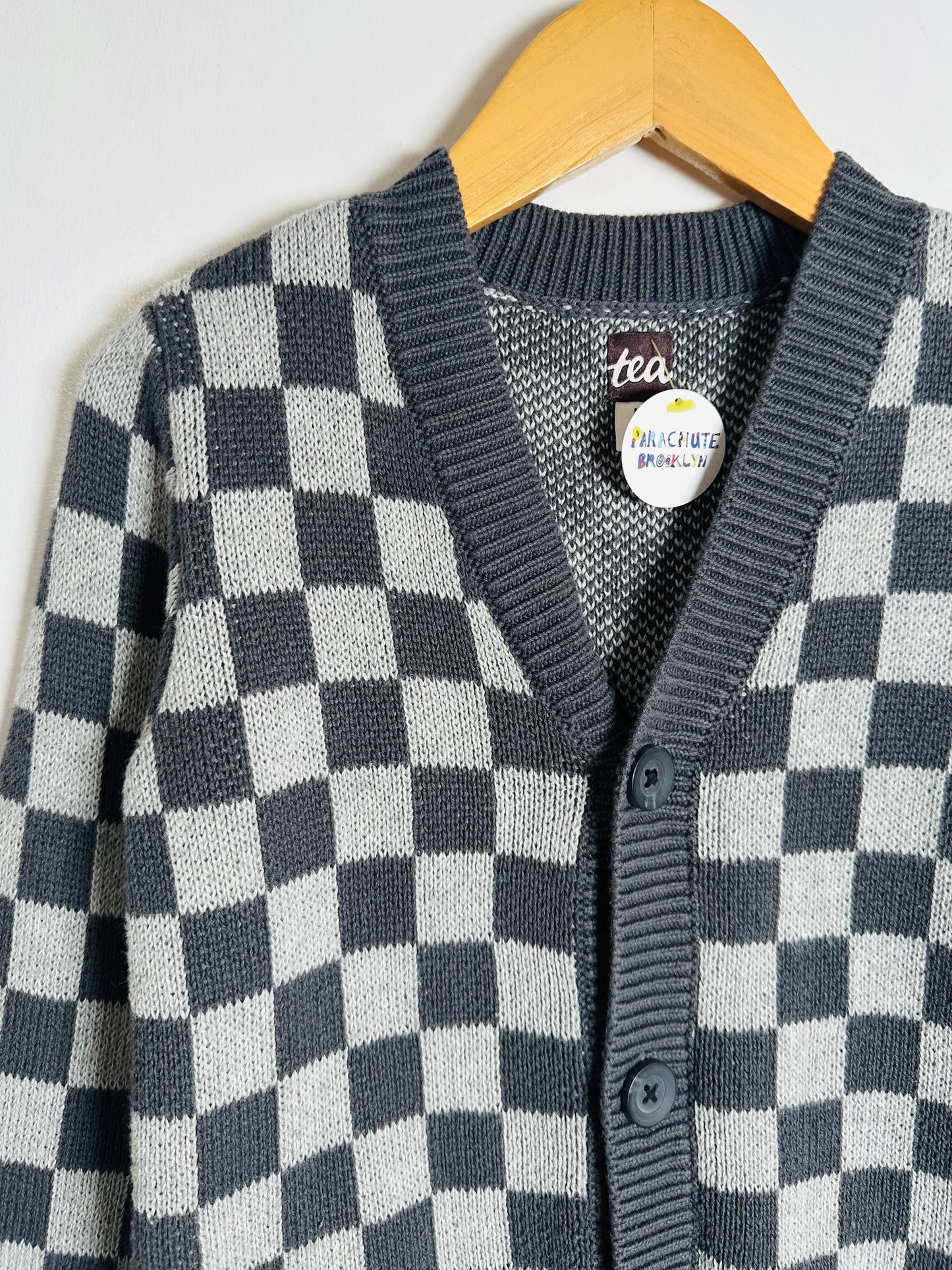 Checkered cardigan on a hanger with a visible brand label.