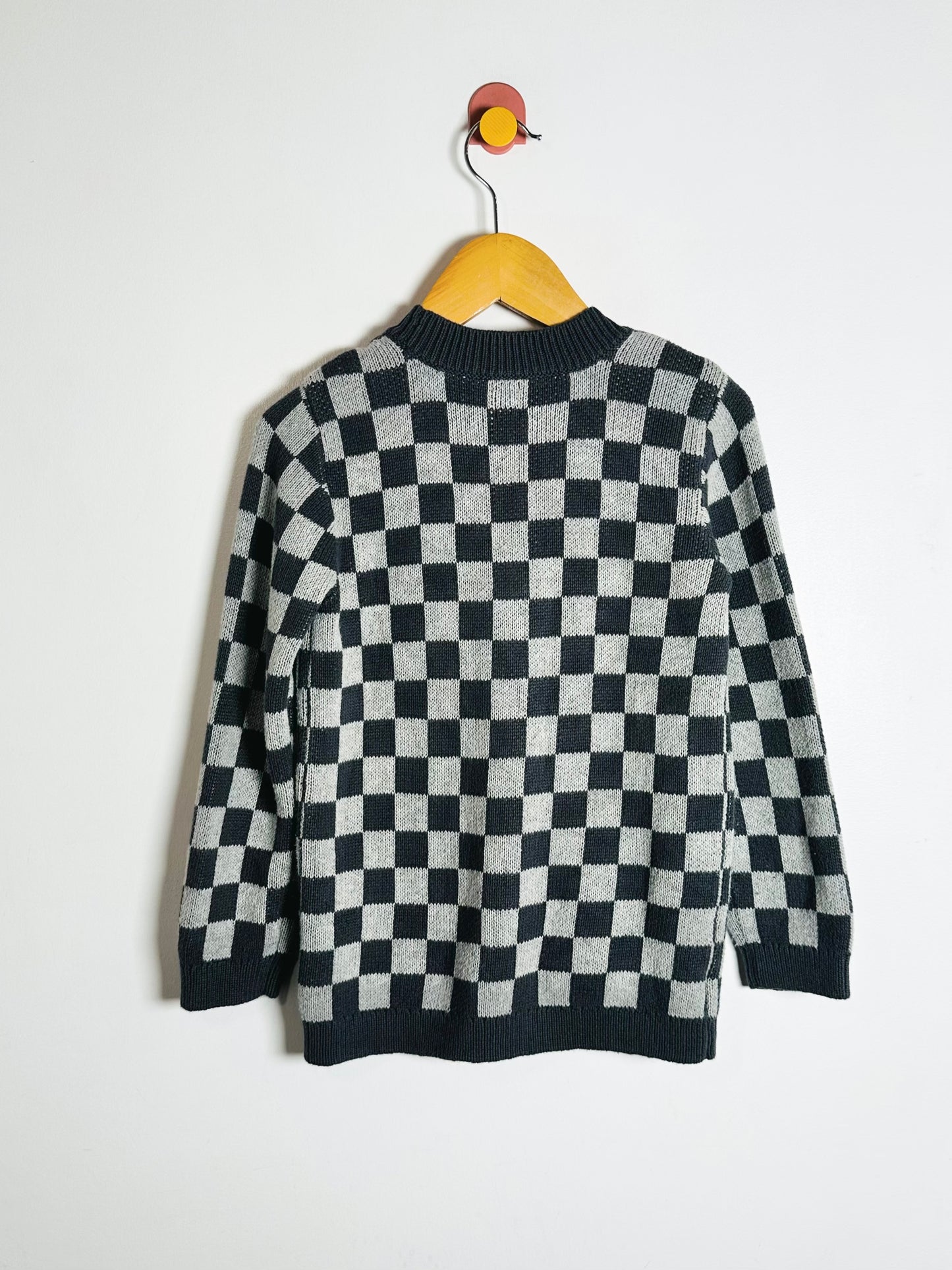 Checkered sweater on a hanger against a white background