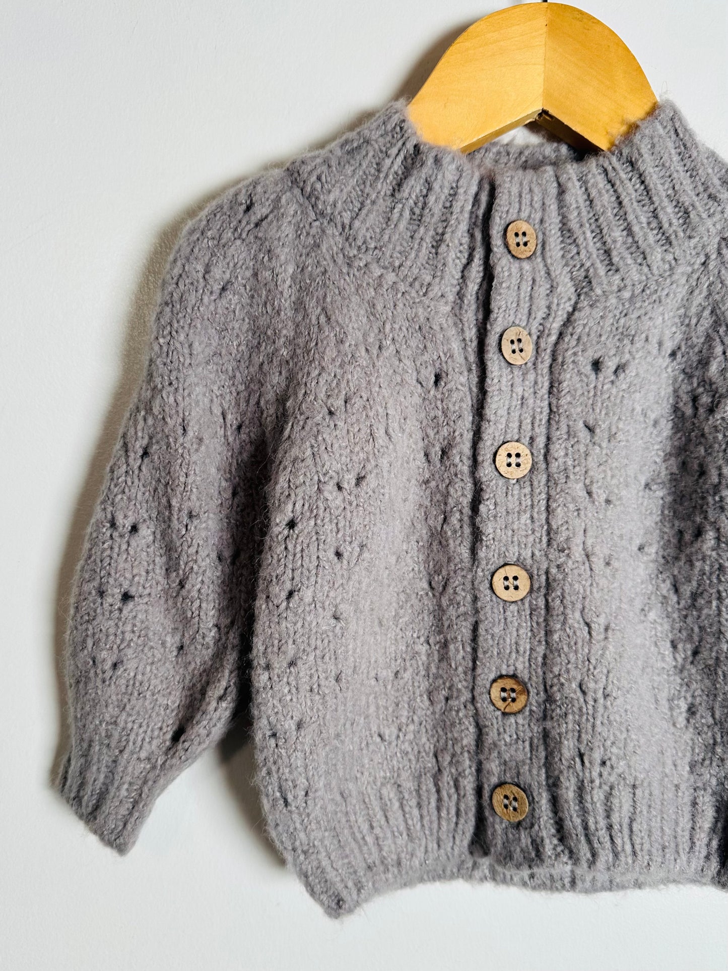 Gray knitted cardigan with wooden buttons on a white background
