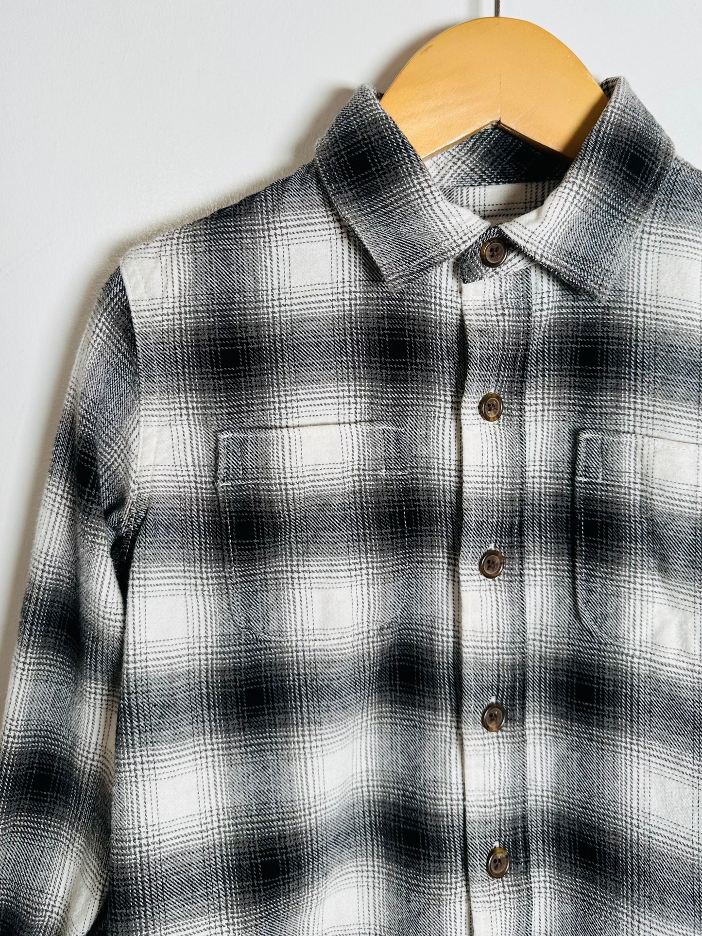 Black and white plaid shirt on a wooden hanger against a white background
