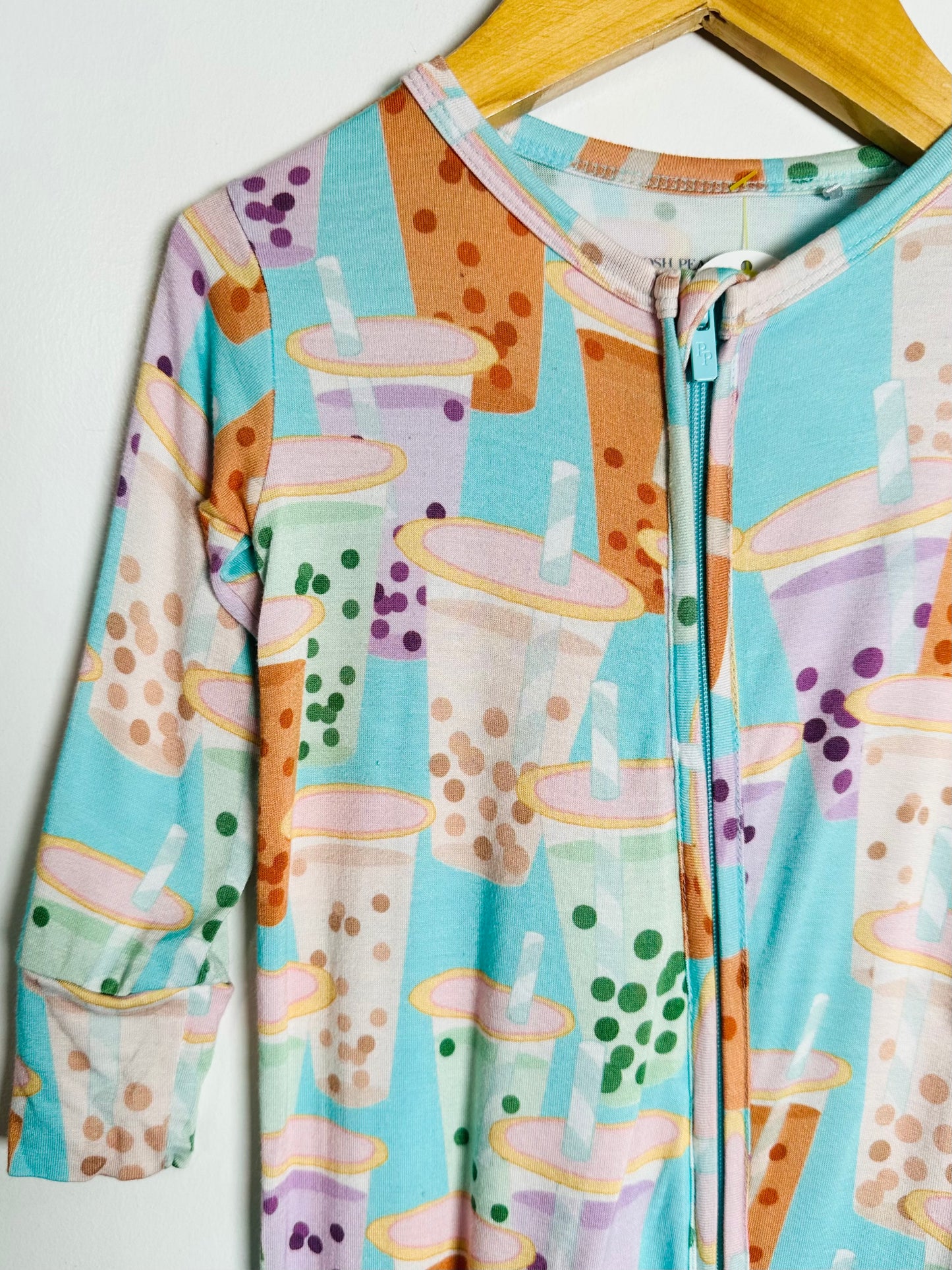 Children's onesie with bubble tea pattern on a hanger against a white background