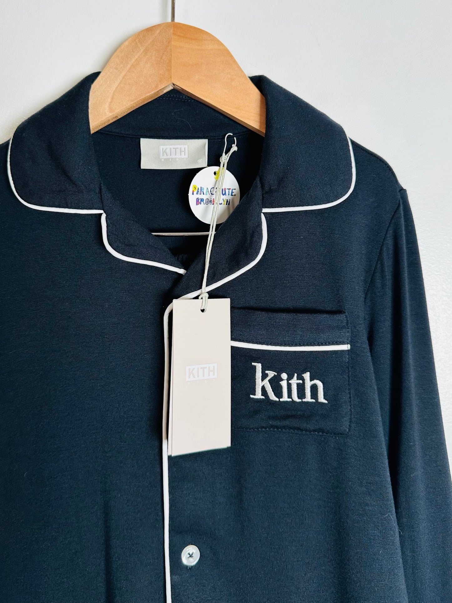 Navy blue shirt with white trim and 'Kith' branding on a hanger.