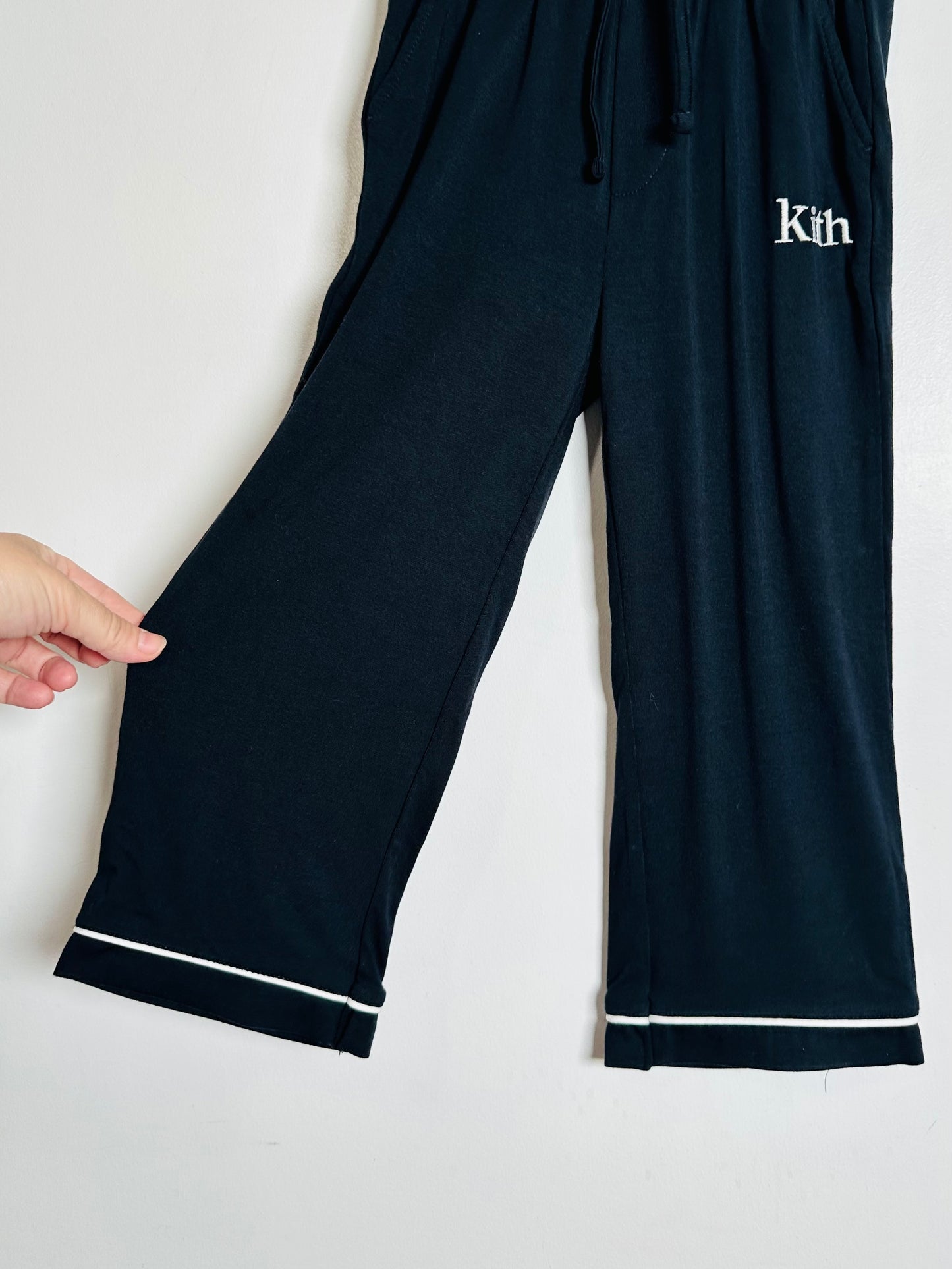 Black pants with white trim and 'Kith' branding on a white background