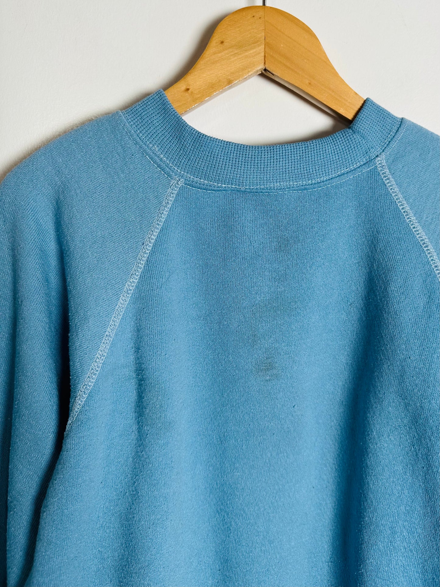 Blue sweater on a wooden hanger against a white background