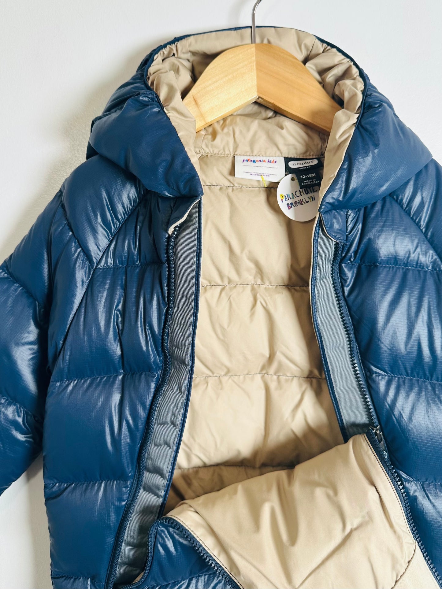 Blue puffer jacket on a hanger with beige interior lining