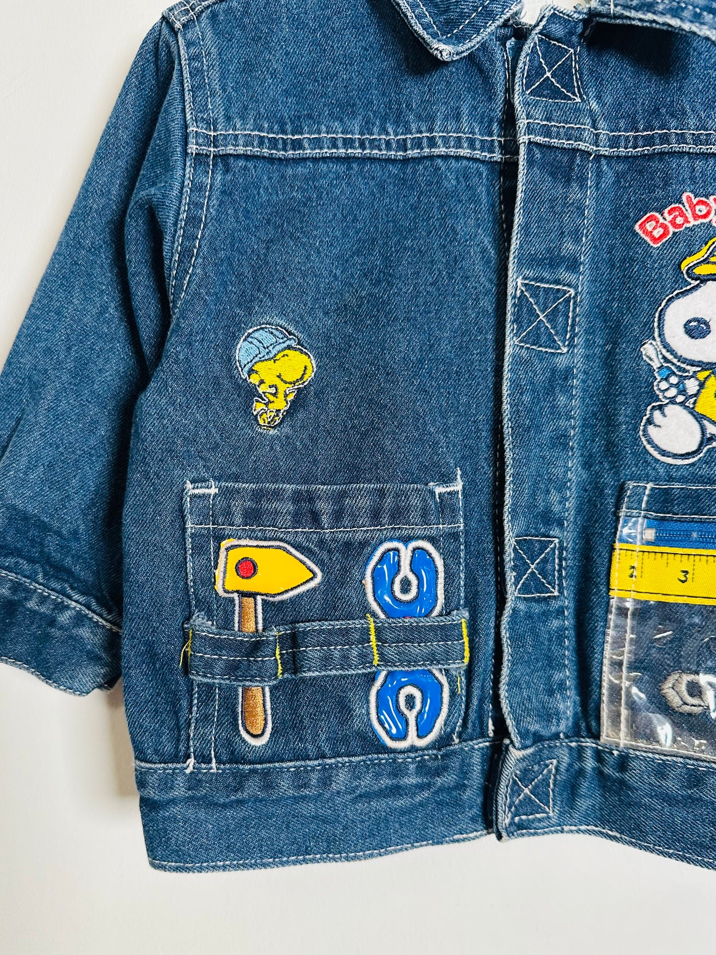 Blue denim jacket with various patches on a light background