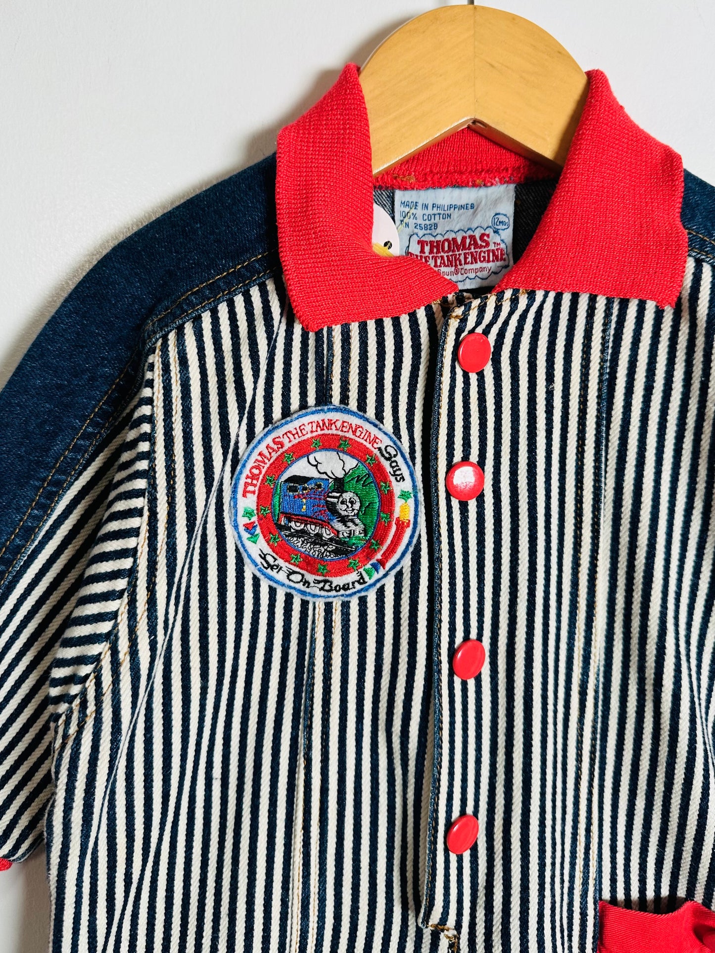 Children's jumpsuit with a Thomas the Tank Engine patch on a hanger