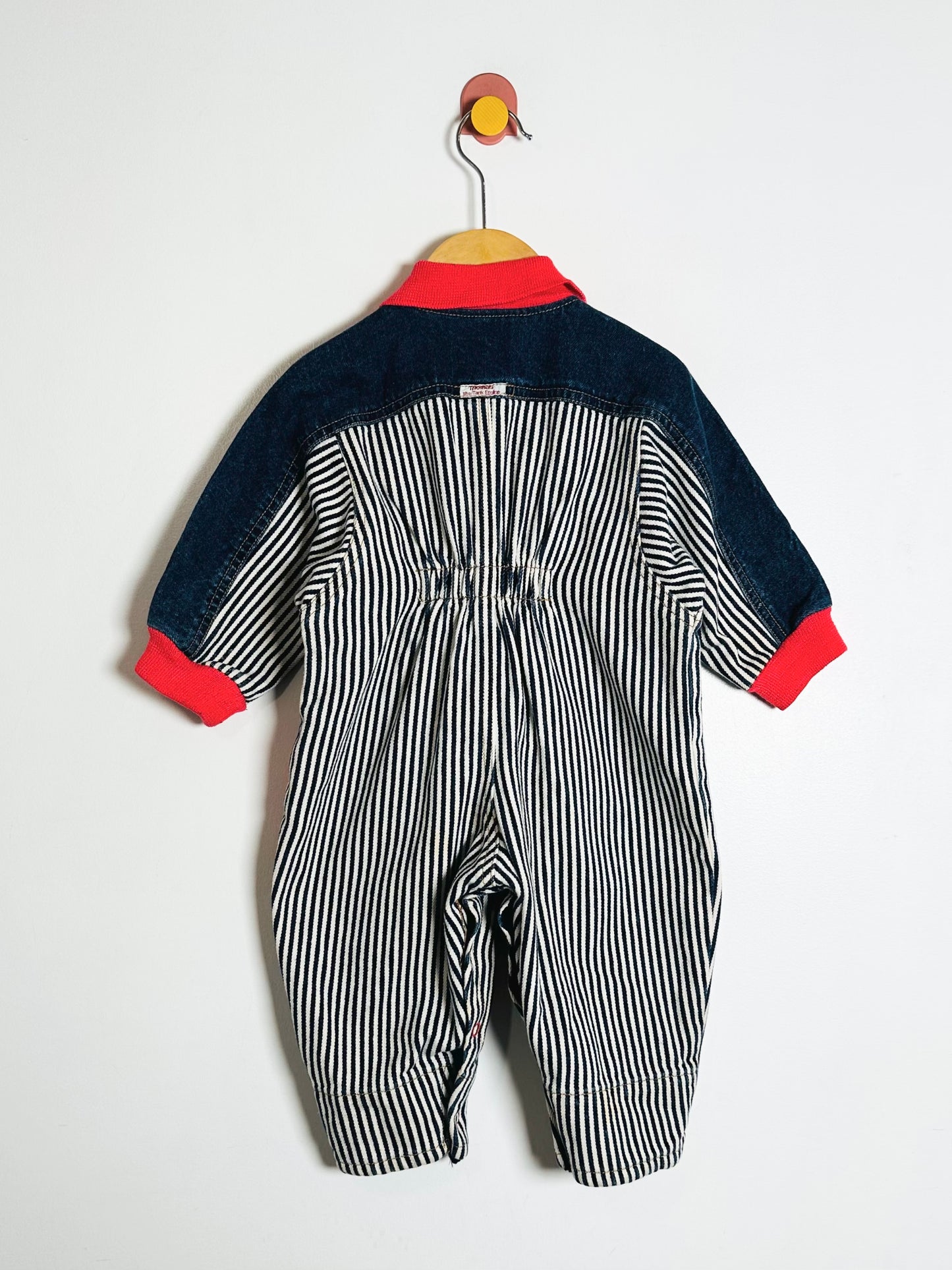 Baby romper with striped pattern and red trim on a white background