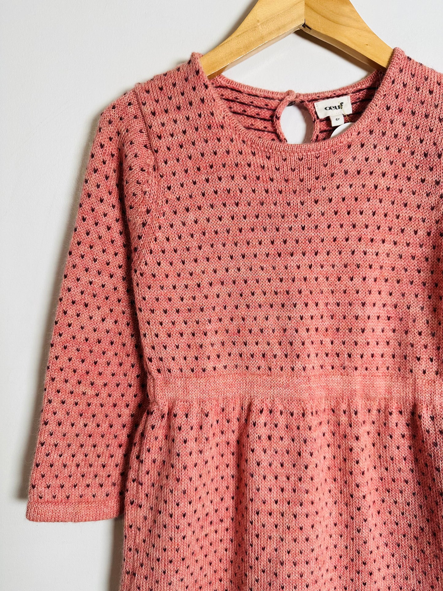 Pink knitted dress on a hanger against a white background