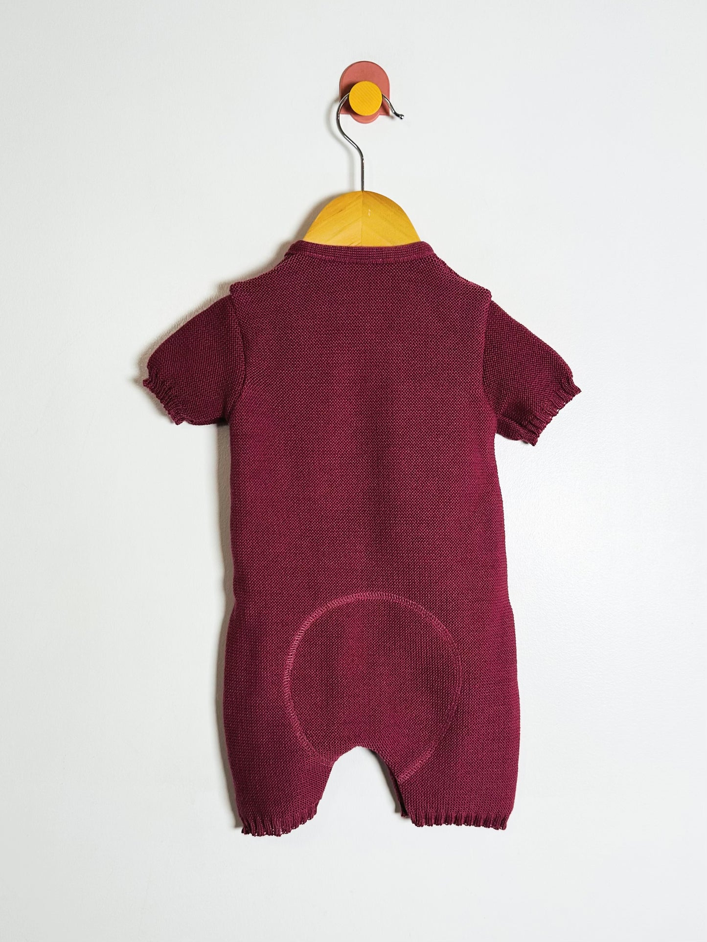 Maroon baby romper on a hanger against a white background