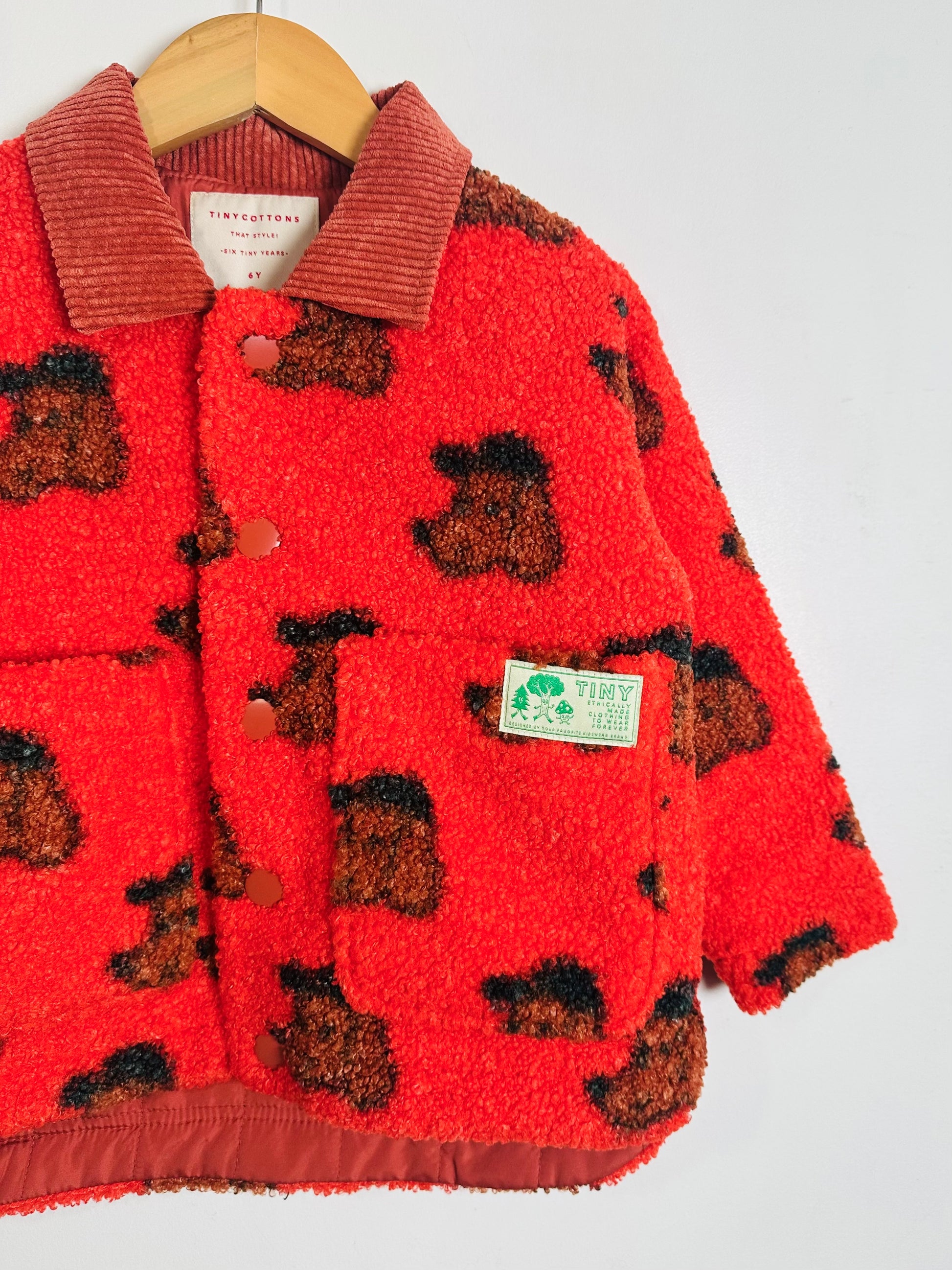 Red children's jacket with brown dog pattern on a white background