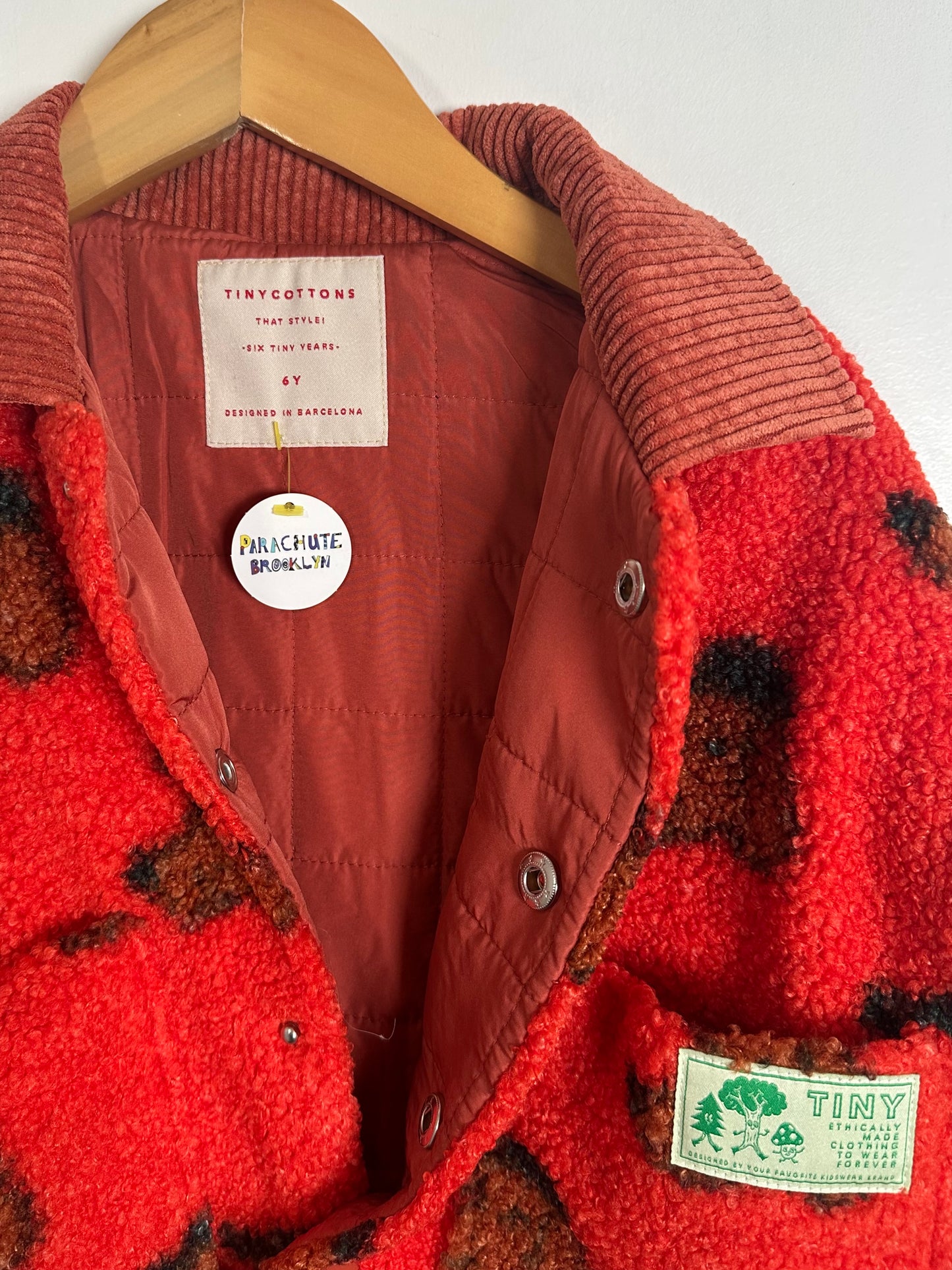 Red and brown jacket with visible brand labels on a white background