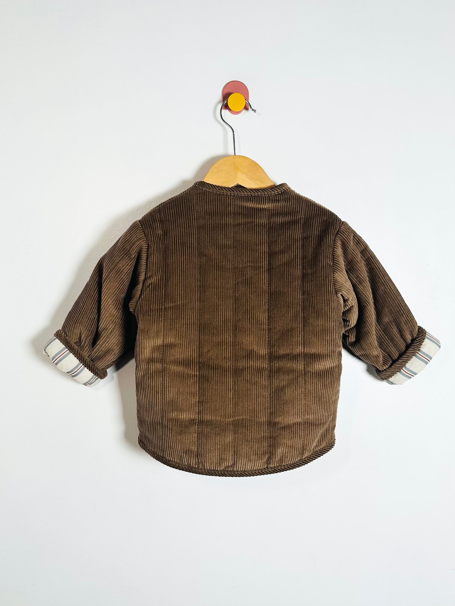 Brown corduroy jacket on a hanger against a white background