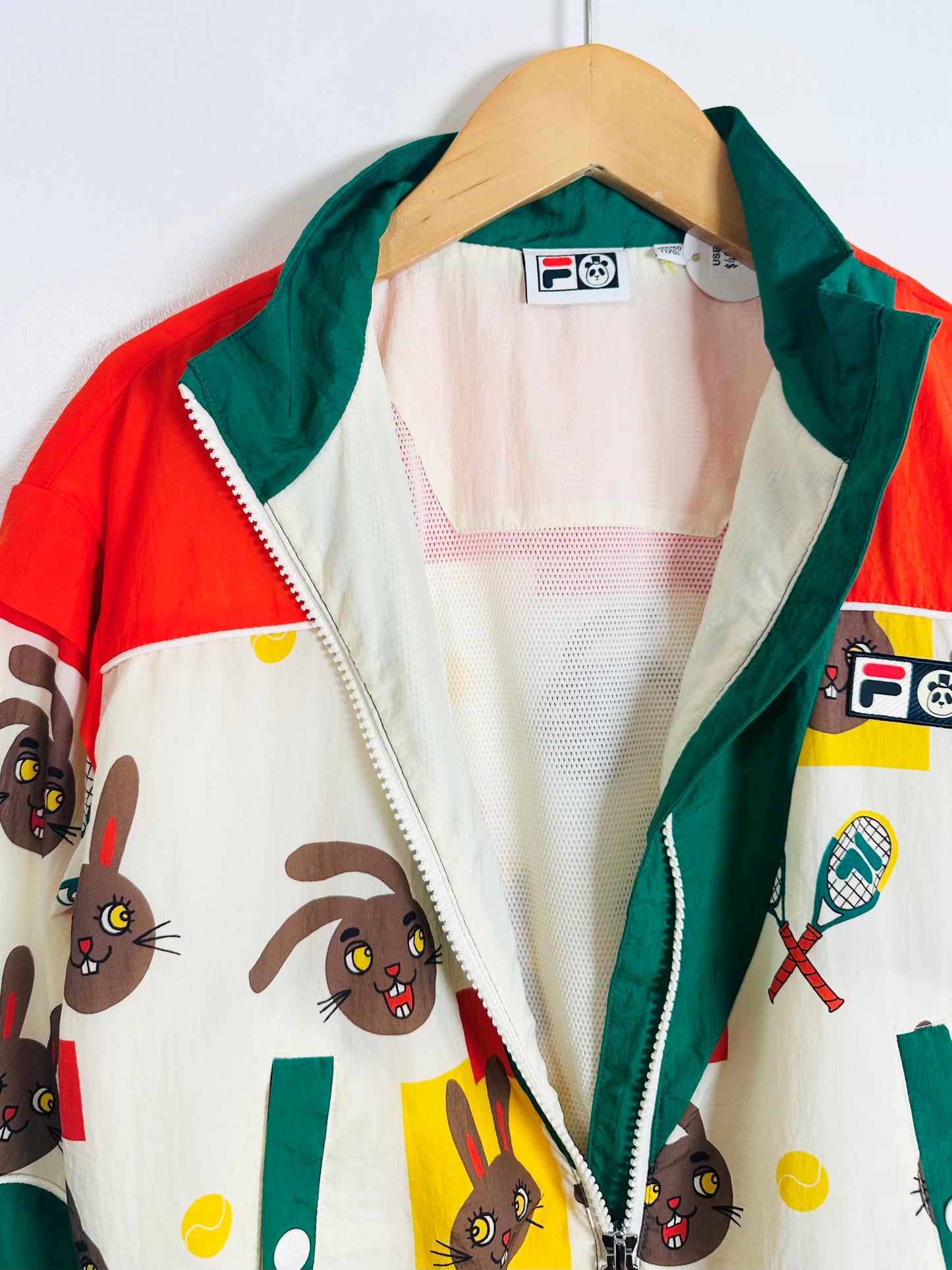 Colorful jacket with cartoon rabbit design on a hanger against a white background