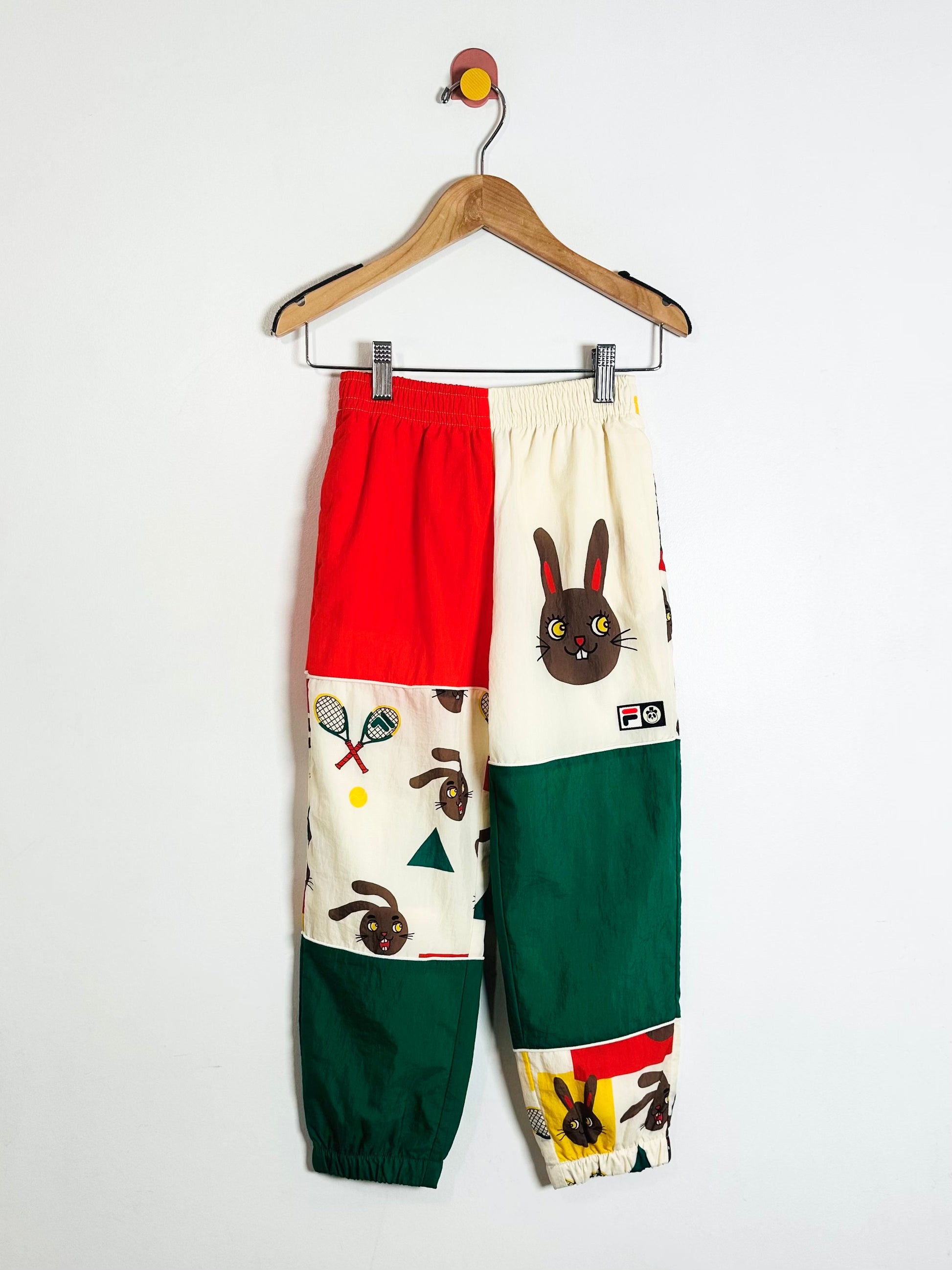 Colorful pants with rabbit design on a hanger against a white background