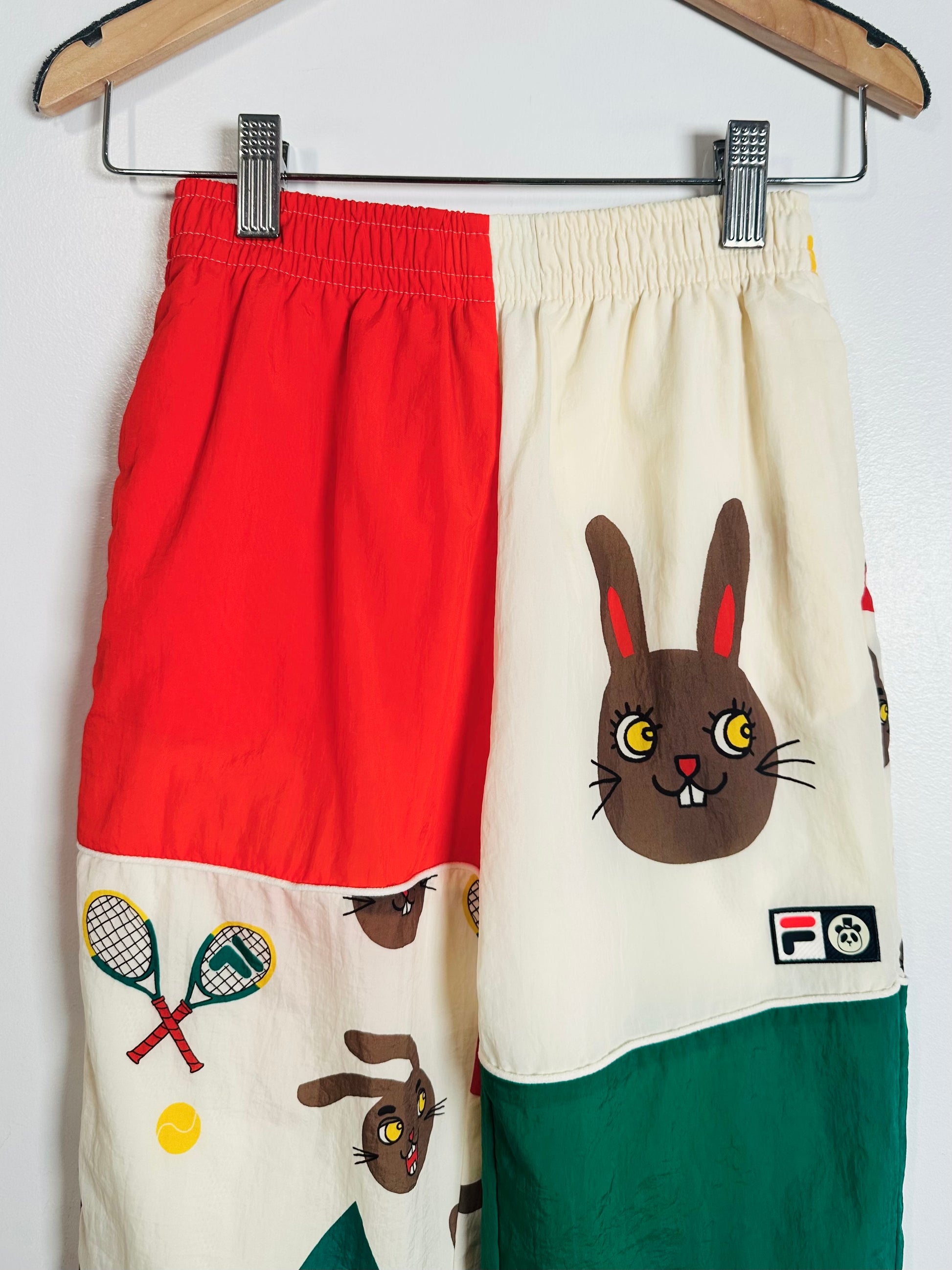 Color-blocked shorts with rabbit design on a hanger against a white background